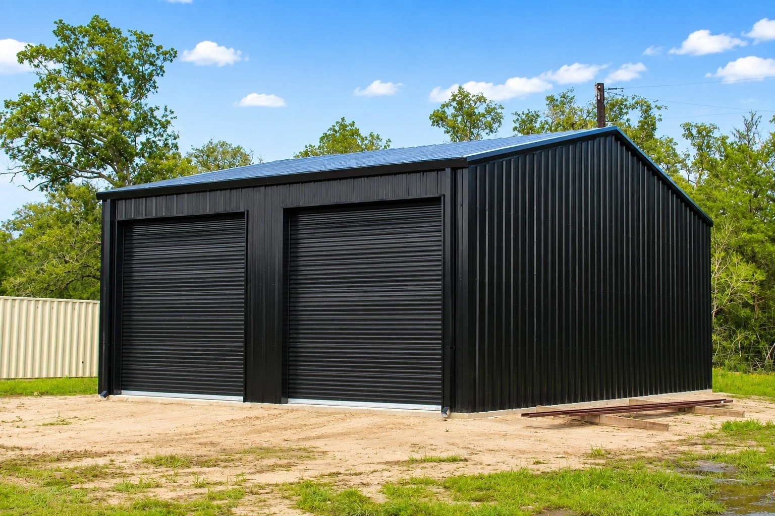 Black on black metal shop building with gutters and downspouts in Ledbetter TX