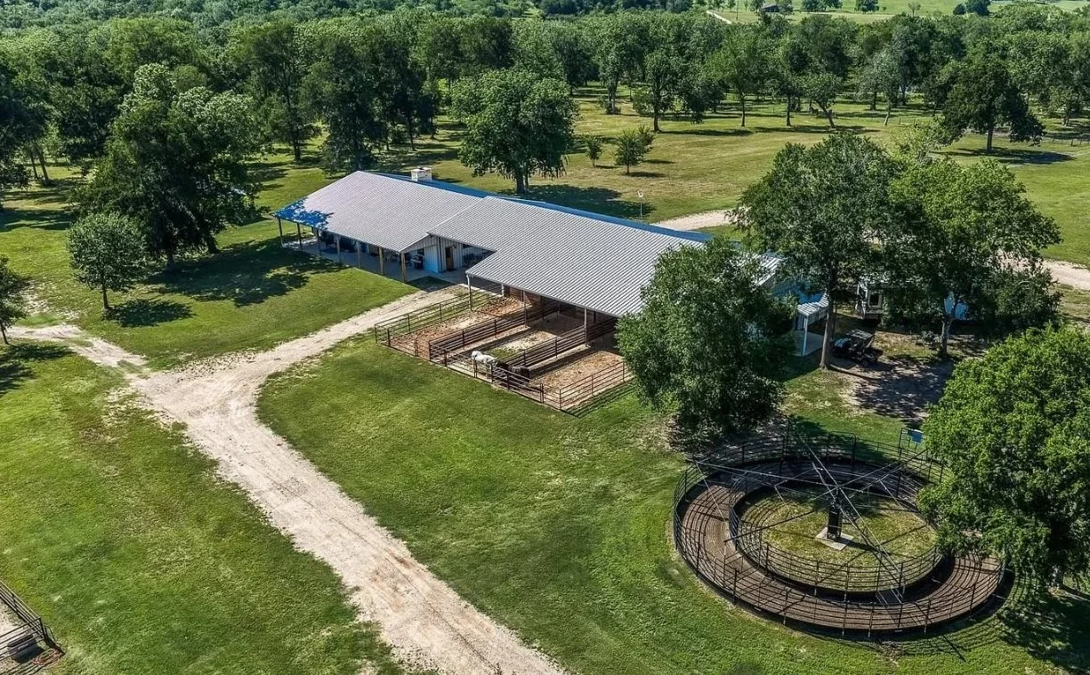Aerial view of a custom 2,400-square-foot barndominium and four-stall horse barn surrounded by rolling pasture in Washington, Texas.