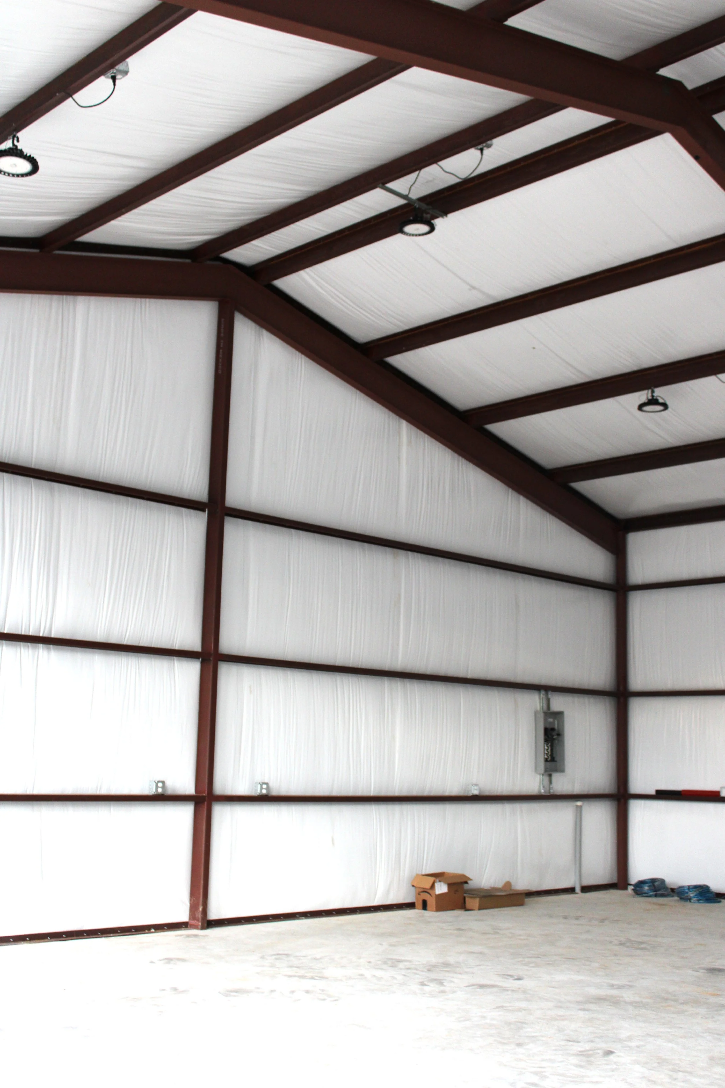 Interior view showing the clear-span red iron frame, insulated walls and roof, and open workspace ready for use.