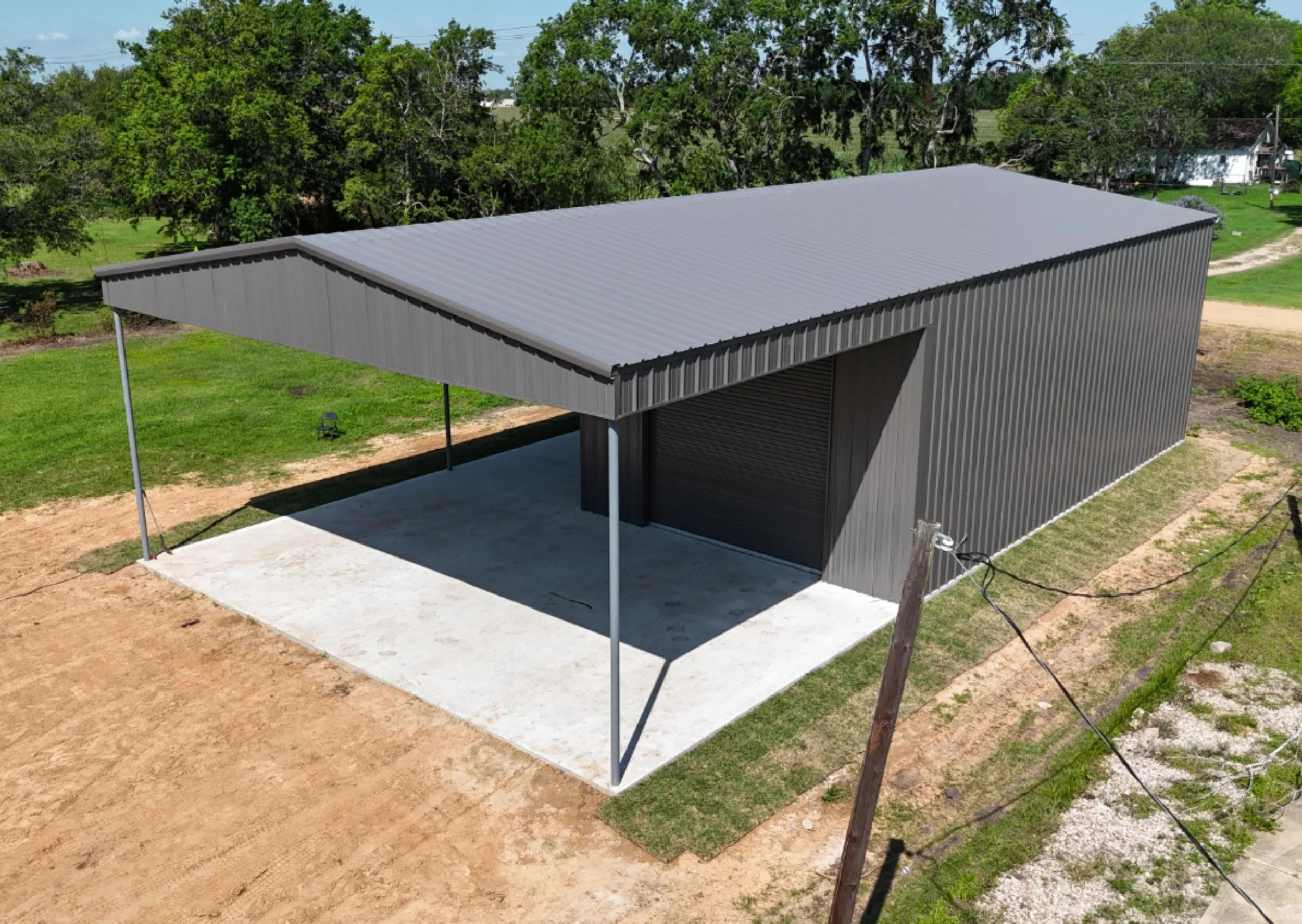 Aerial view of custom weld-up metal building in Richmond TX with enclosed shop, front awning, and charcoal grey metal siding