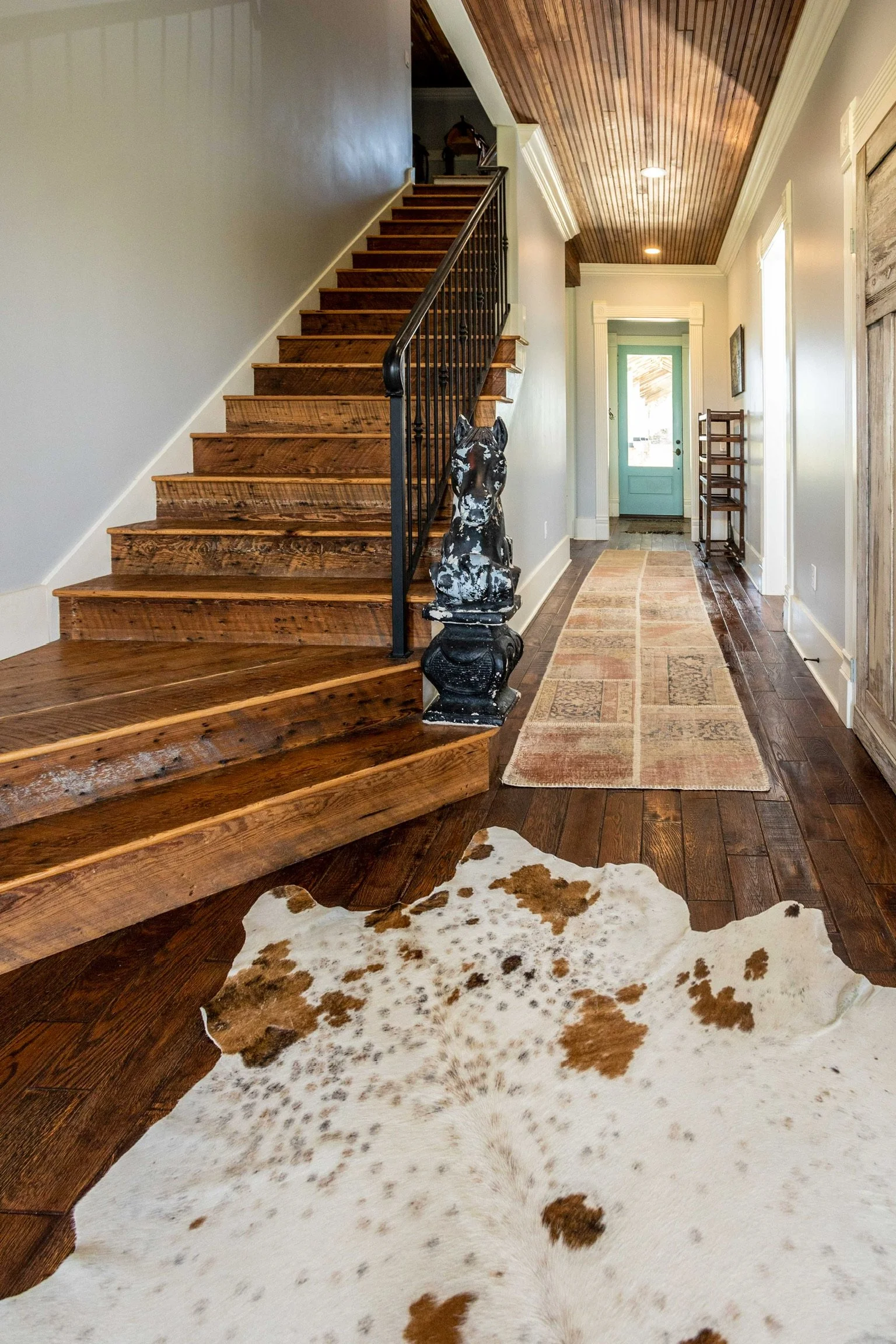 A welcoming front entrance featuring a custom antique door, decorative iron glass panels, and a glimpse into the home's luxurious primary suite. Every detail was selected to create a warm first impression.