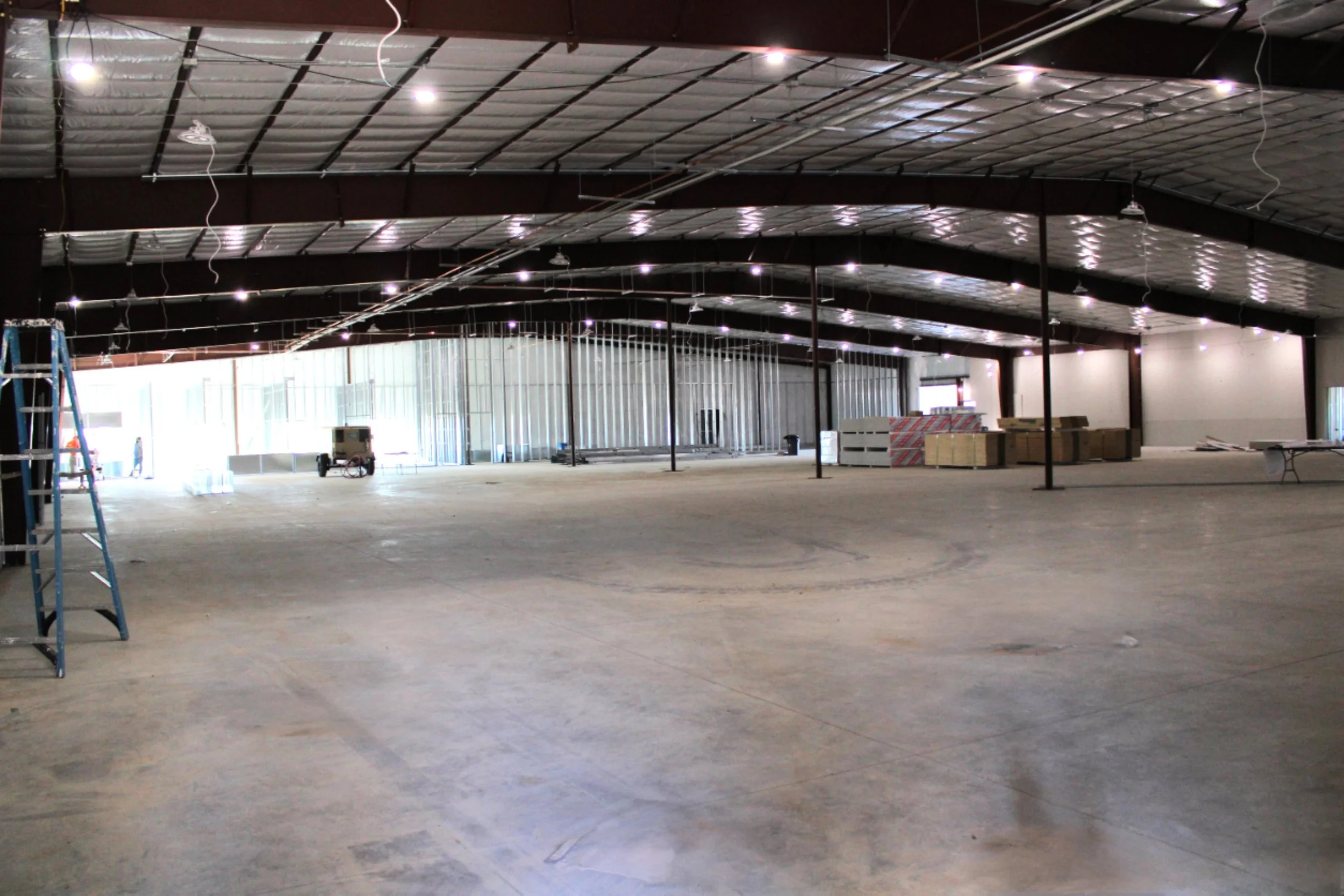 Interior view of a commercial metal building in Bryan, TX with open clear-span layout, insulated ceiling panels, and finished concrete floor for commercial operations.