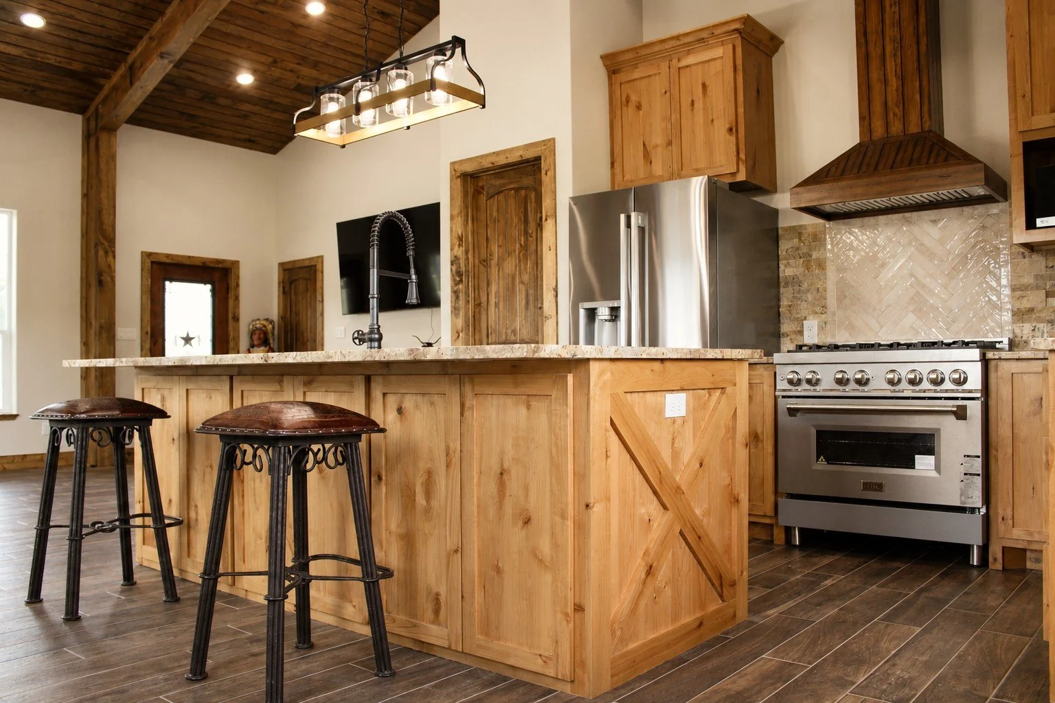 Custom farmhouse kitchen featuring granite countertops, wood cabinetry, and stainless appliances inside Texas barndominium