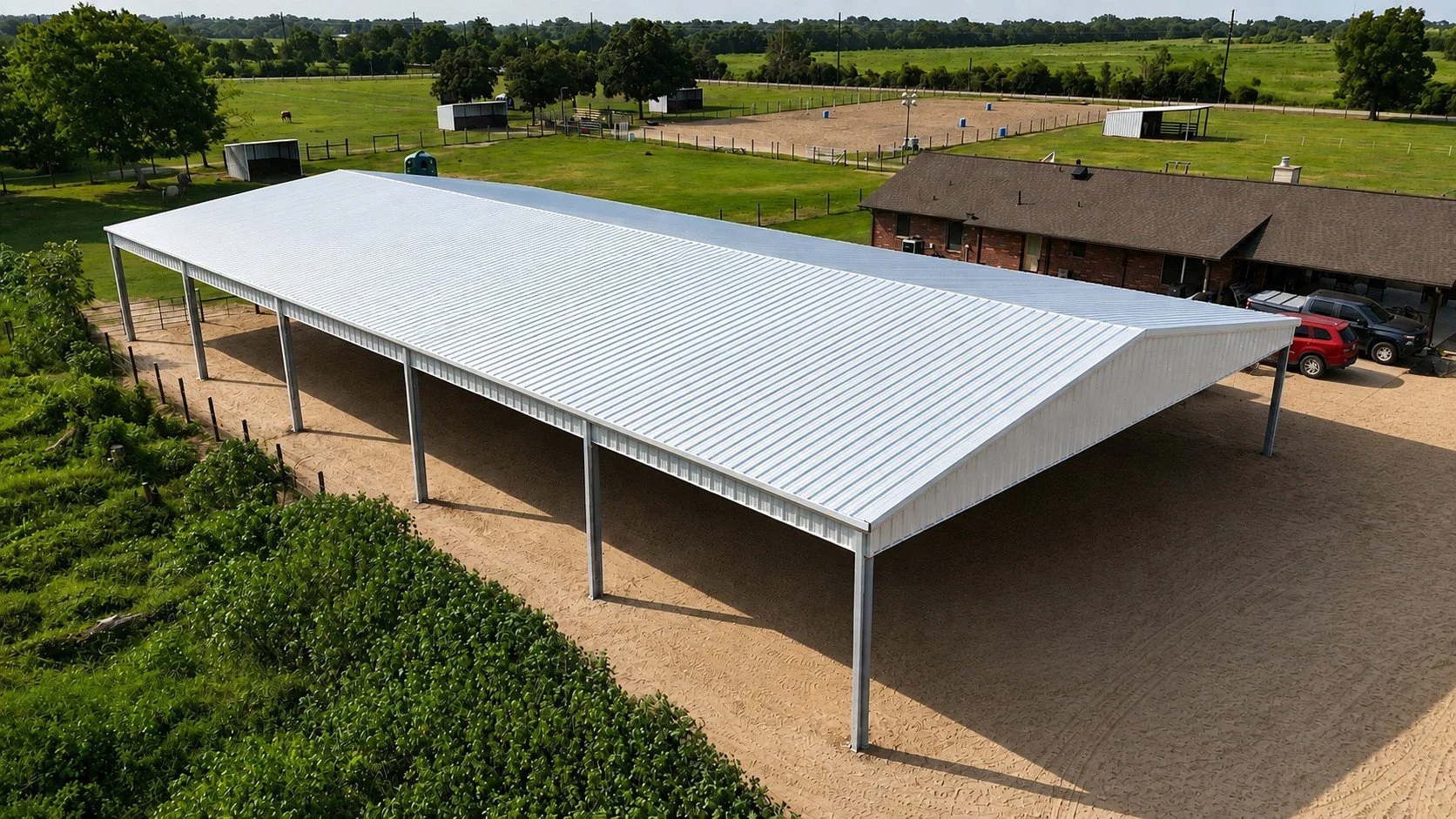 Aerial view of a custom steel covered riding arena with open sides and Galvalume roof in Needville, Texas.