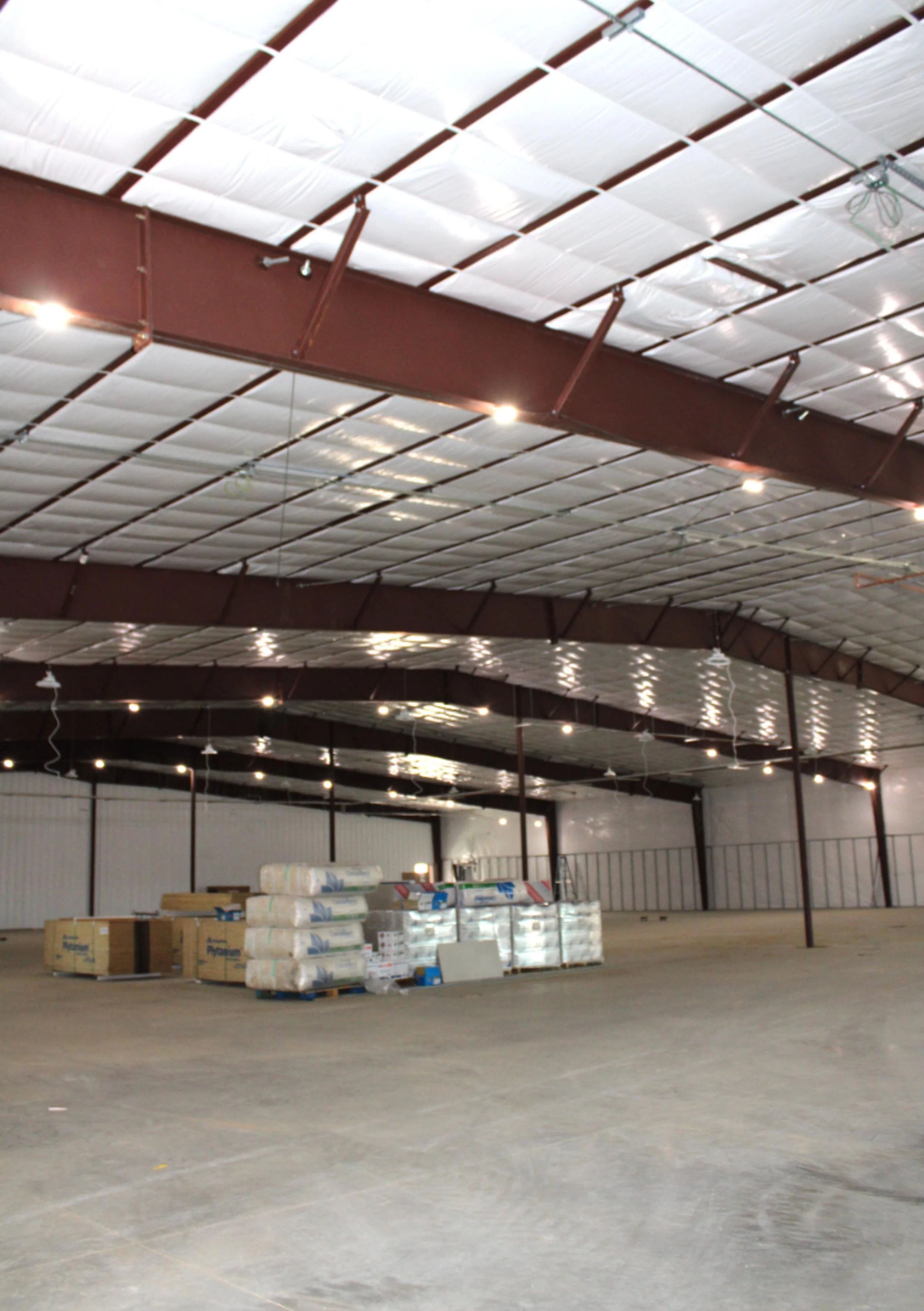 Interior of a commercial metal building in Bryan, TX featuring clear-span steel framing, insulated ceiling, and open floor space designed for commercial and industrial use.