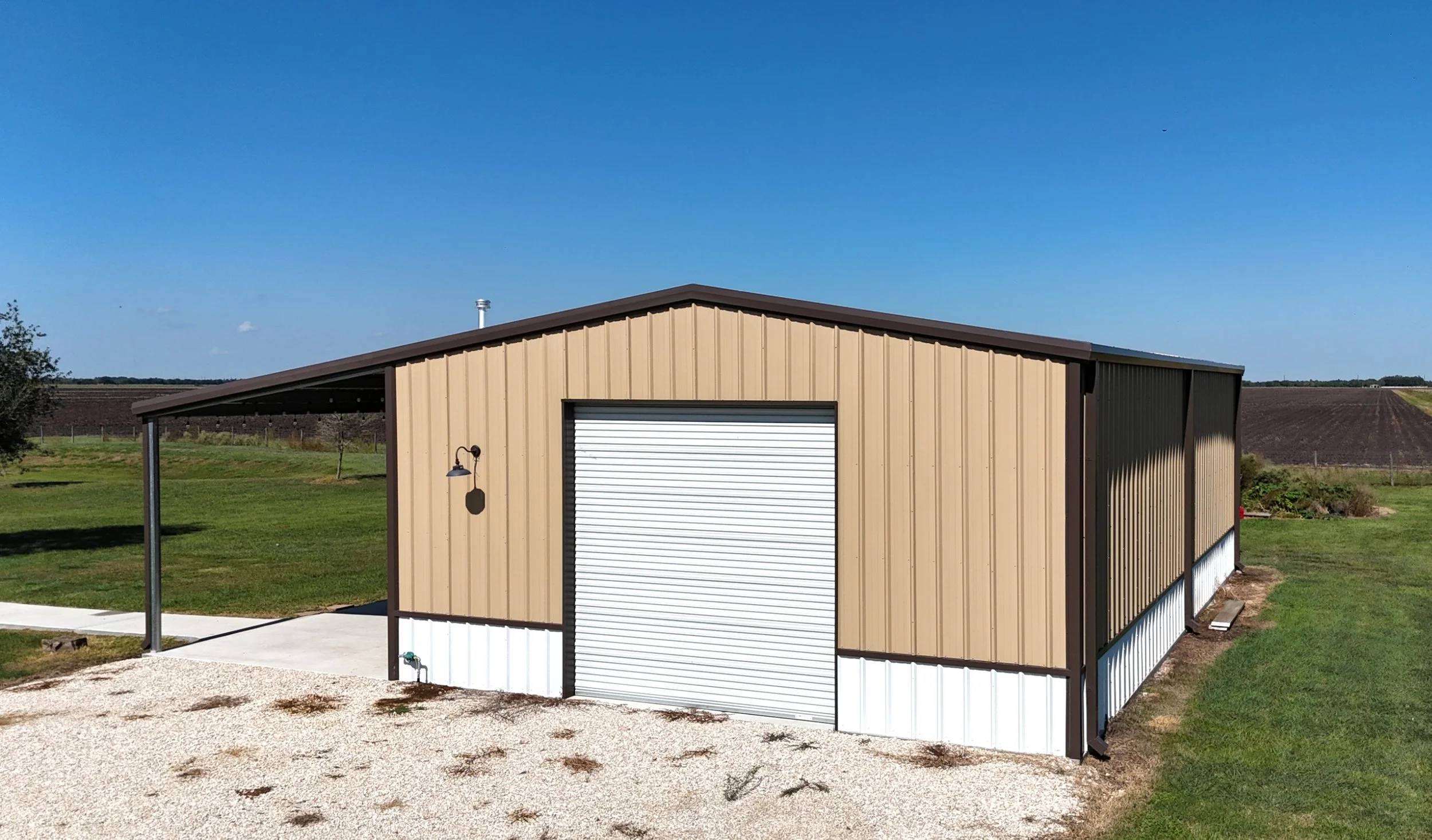 Custom metal shop and garage with covered porch lean-to, roll-up door, and white wainscot, built in Fort Bend County, Texas.