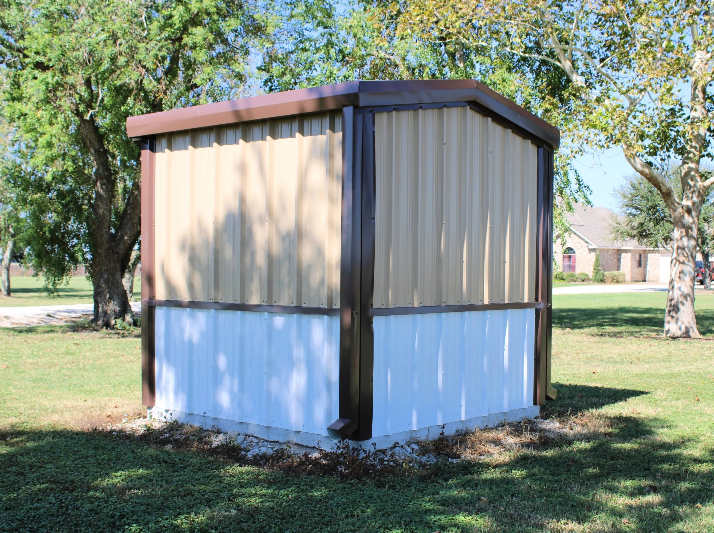 Side view of matching metal well house with two-tone siding and white wainscot, built in Fort Bend County, Texas.