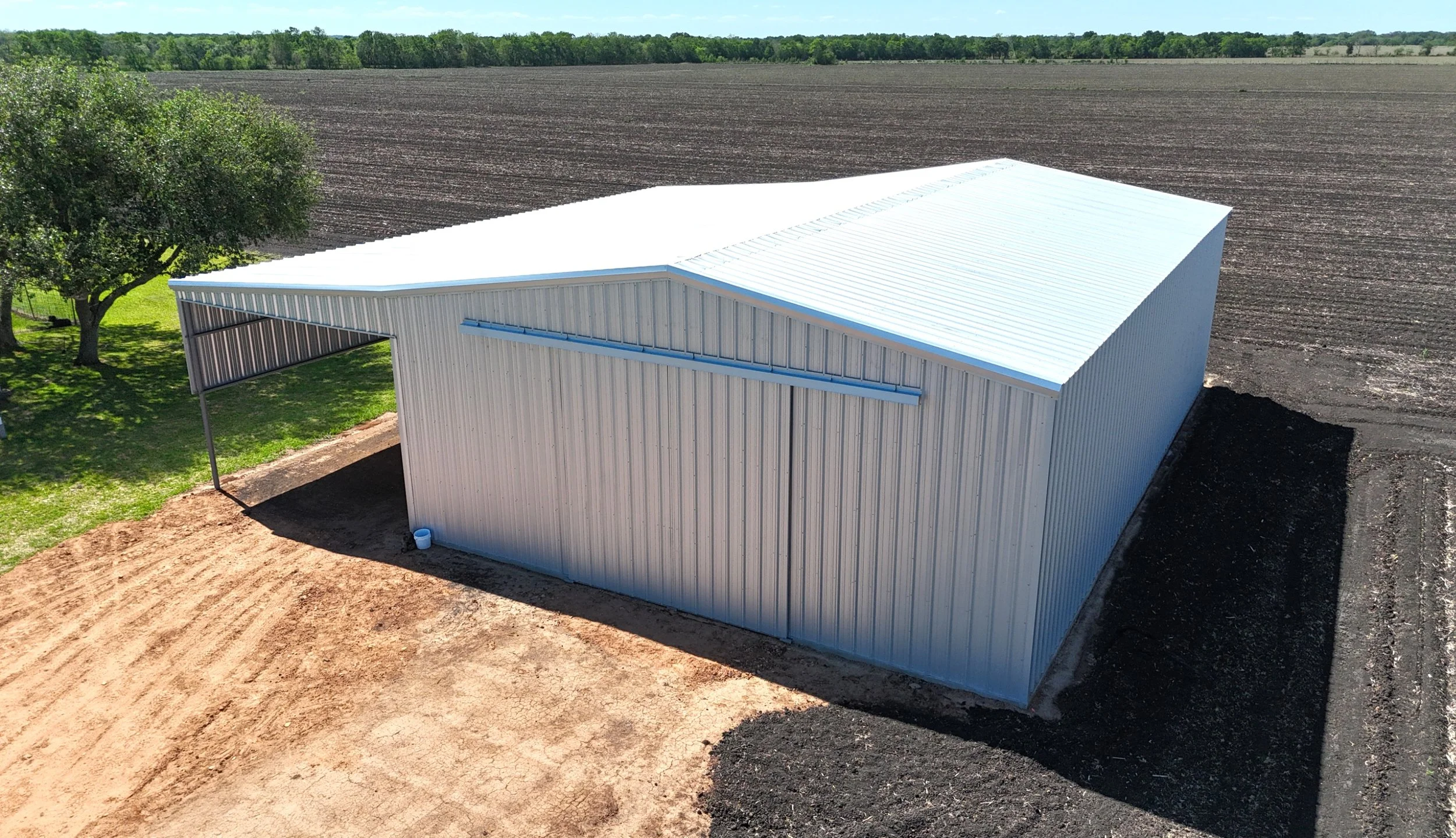 Metal agricultural building with extended lean-to for equipment storage, galvalume finish, East Bernard TX