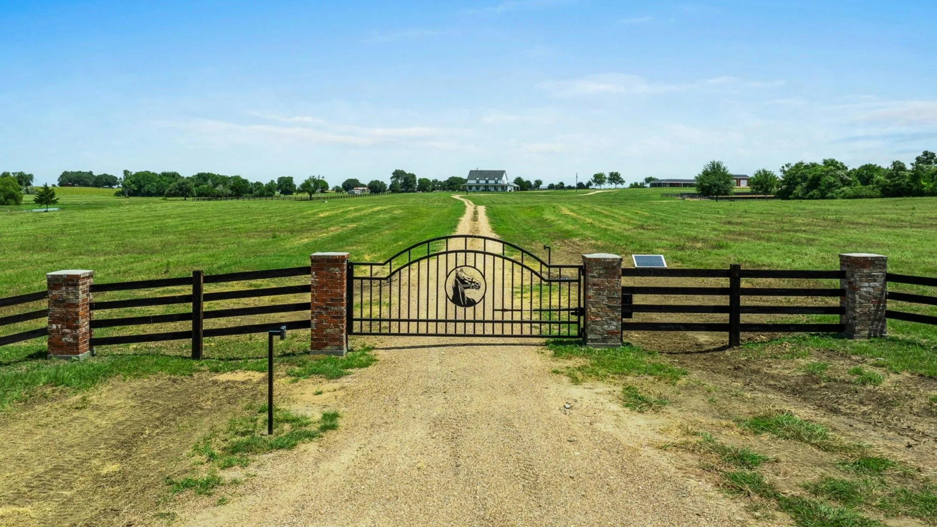 Custom metal gate with horse head and brick pillars near New Ulm Texas.