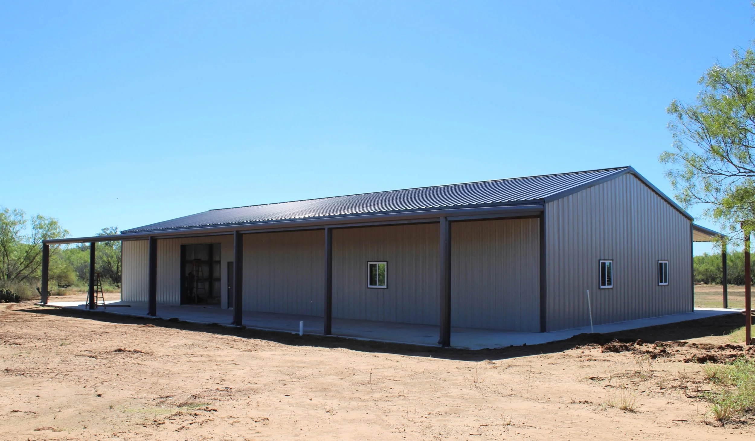90x40 metal building with two 15x90 lean-to extensions, insulated roof and walls, and gutter system installed on South Texas ranch land.
