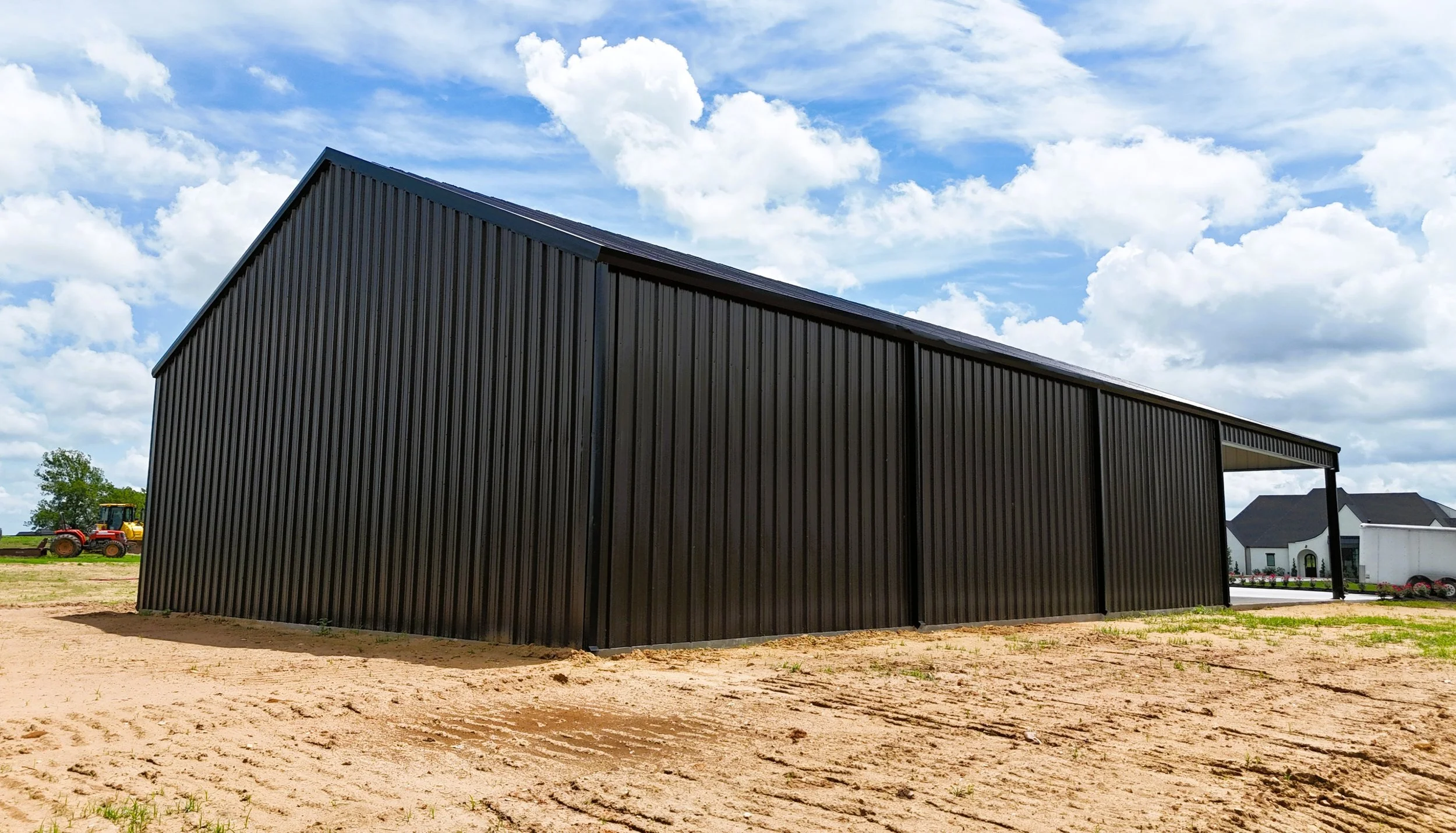 Side angle of insulated metal shop building in Washington County, Texas showcasing the steep 5/12 roof pitch, full black trim package, and durable 26 gauge steel siding designed for long-term performance.
