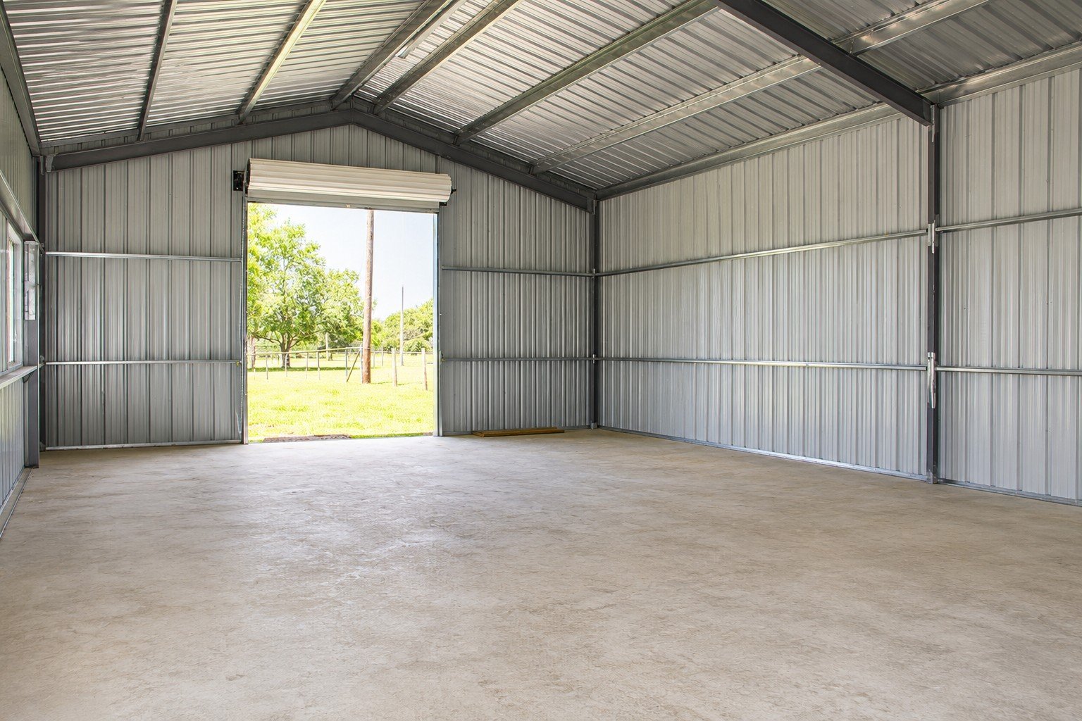Open interior showcasing the clear-span design, galvanized roof and wall purlins, and reinforced concrete floor.