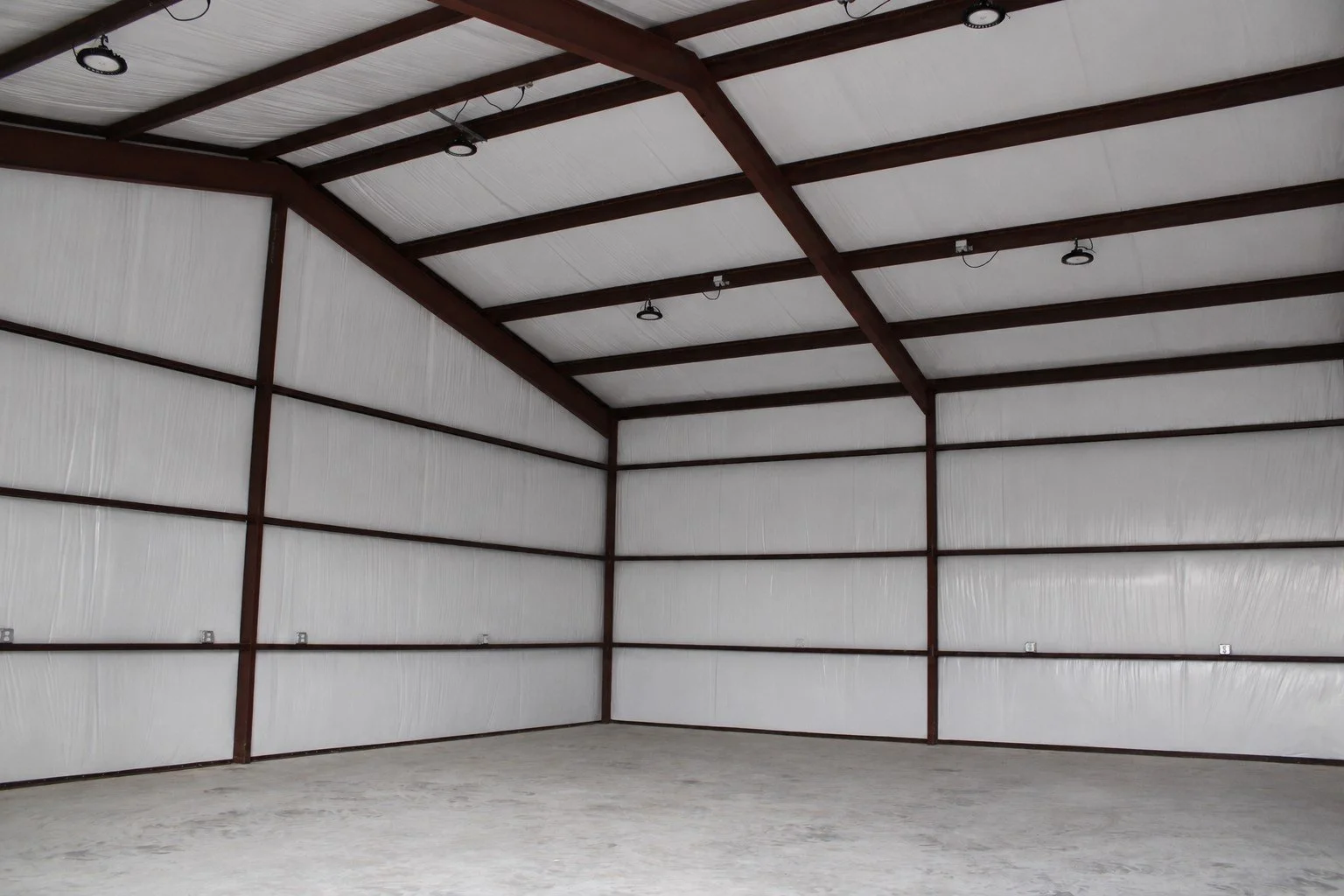 Interior view showing the clear-span red iron frame, insulated walls and roof, and open workspace ready for use.