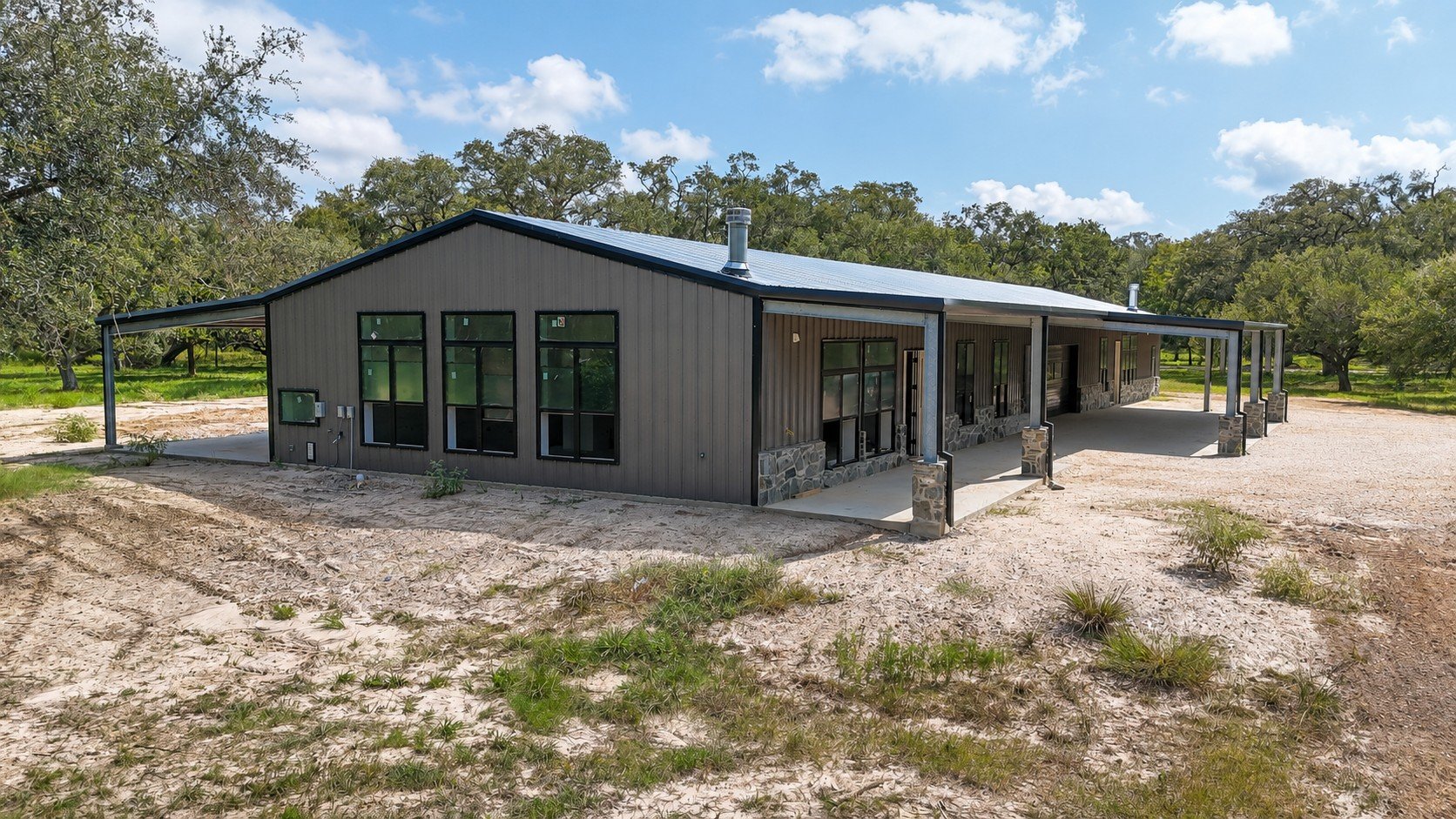 Front exterior view featuring black-framed windows, Charcoal Gray siding, black trim, and stone-wrapped porch columns.