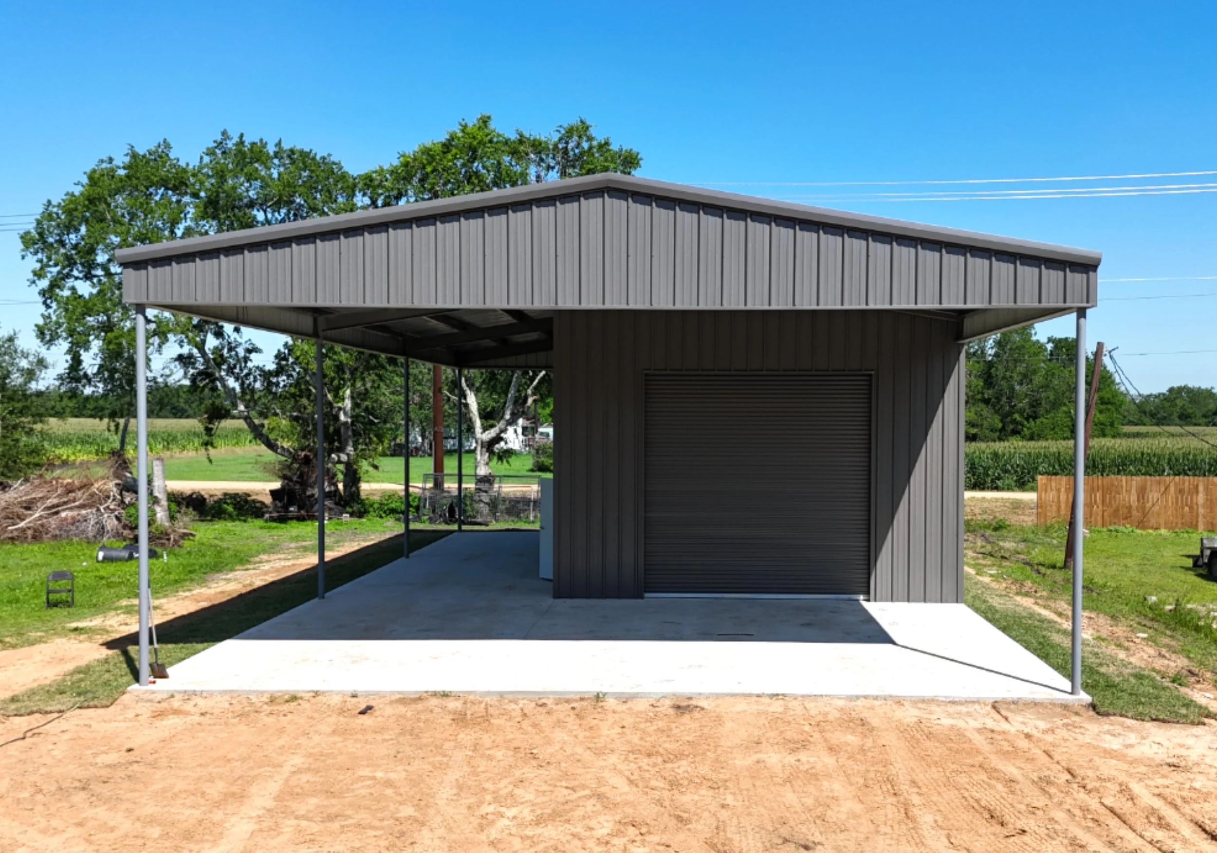 Custom boat storage metal building in Richmond TX with front awning, charcoal grey roll-up door, and full concrete slab