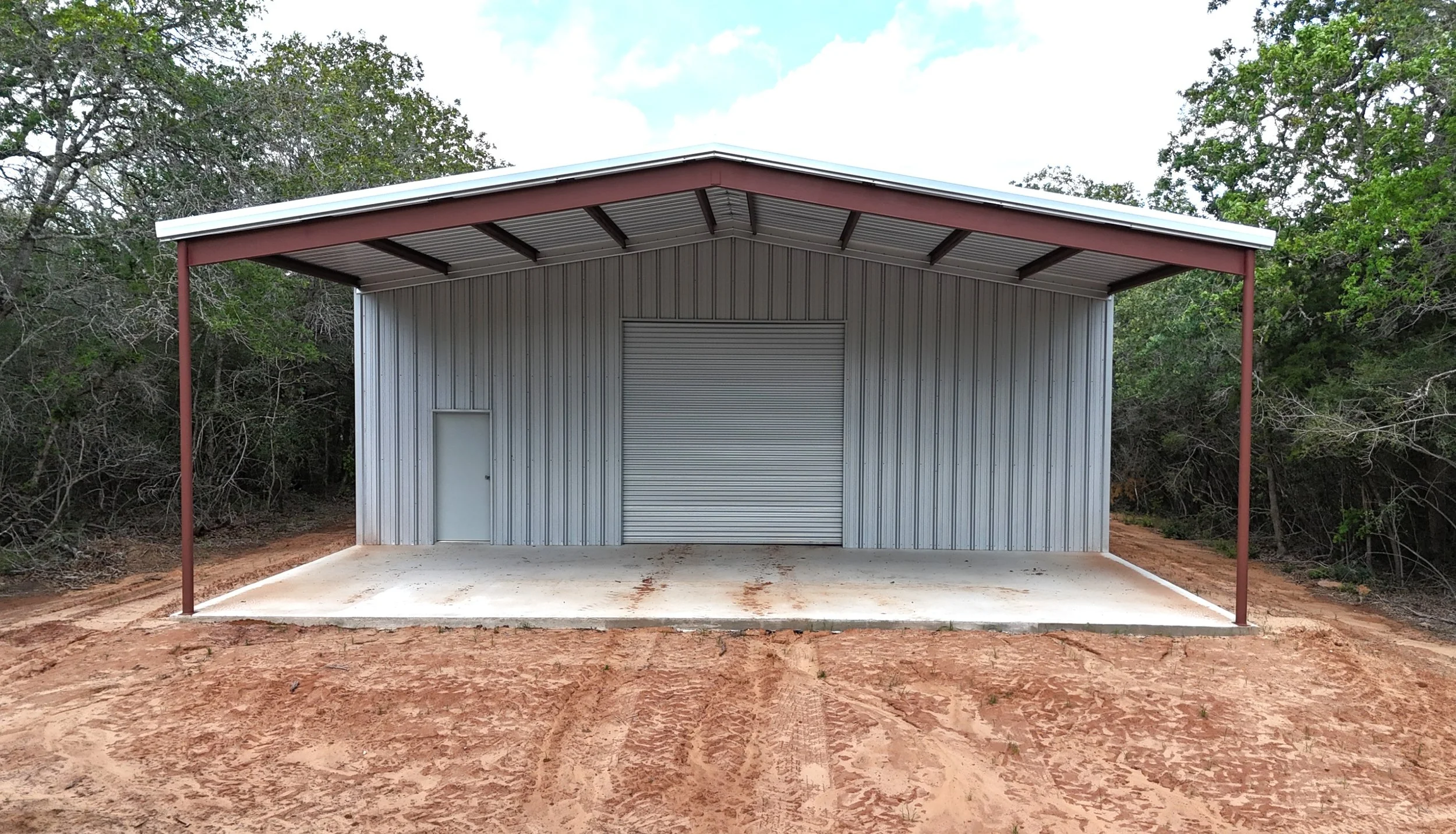Front view of custom metal shop with 40x20 covered awning, 12x12 roll-up door, and walk door in Waelder, Texas