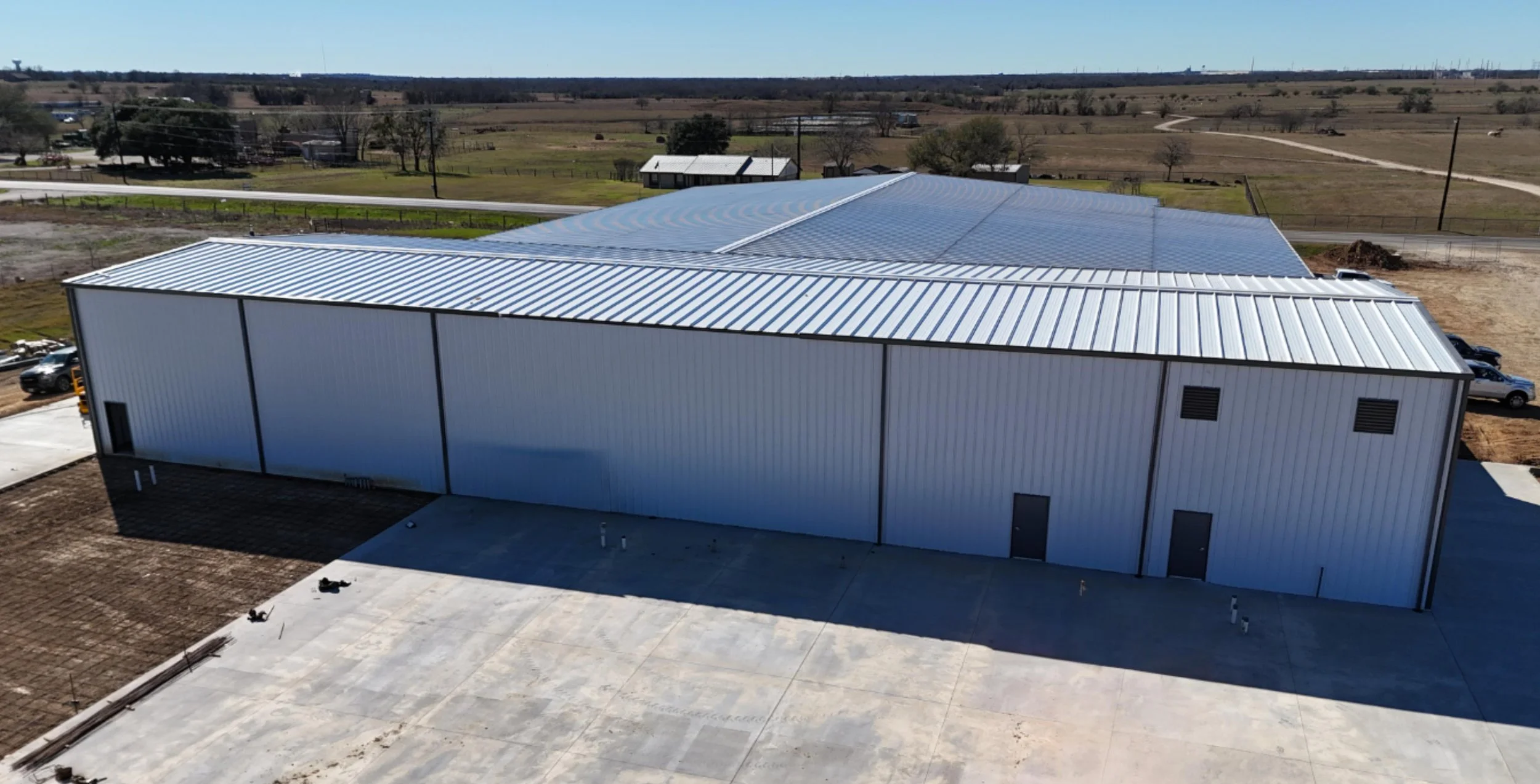 Rear view of a commercial metal building in Bryan, TX showing steel wall panels, insulated roof system, and concrete service area designed for commercial operations.