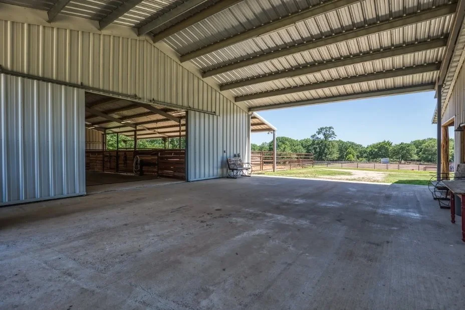 Large covered breezeway connecting the barndominium to the horse barn and providing a sheltered workspace for daily ranch operations.