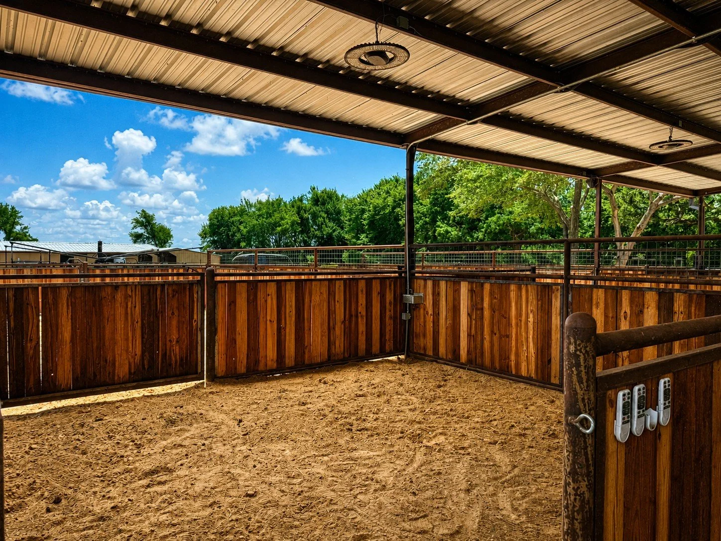 Custom welded horse stalls with creosote board walls and steel pipe construction inside a covered horse barn in Caldwell, TX.