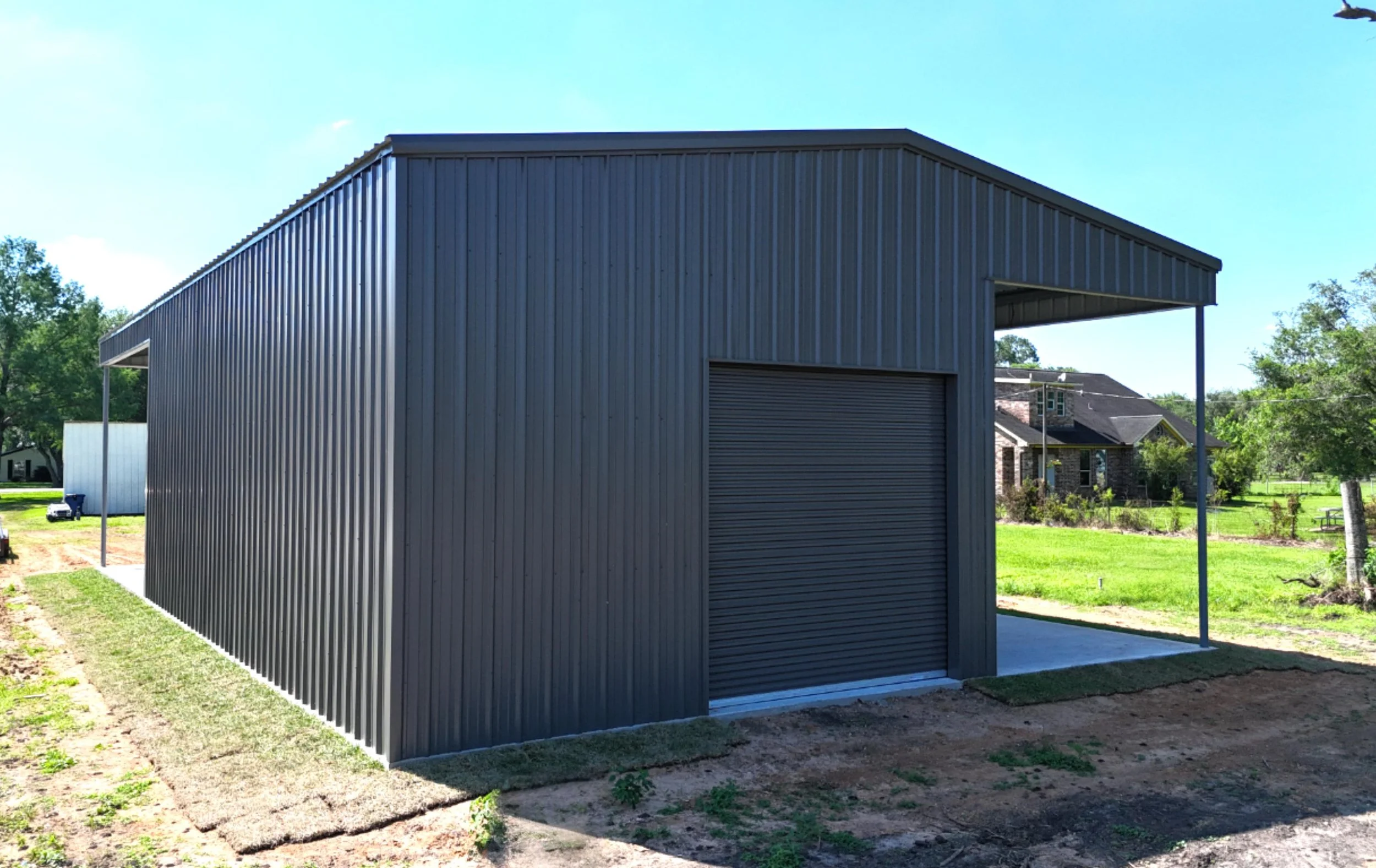 Rear view of insulated metal shop building in Fort Bend County TX with 14x14 roll-up door and covered lean-to space