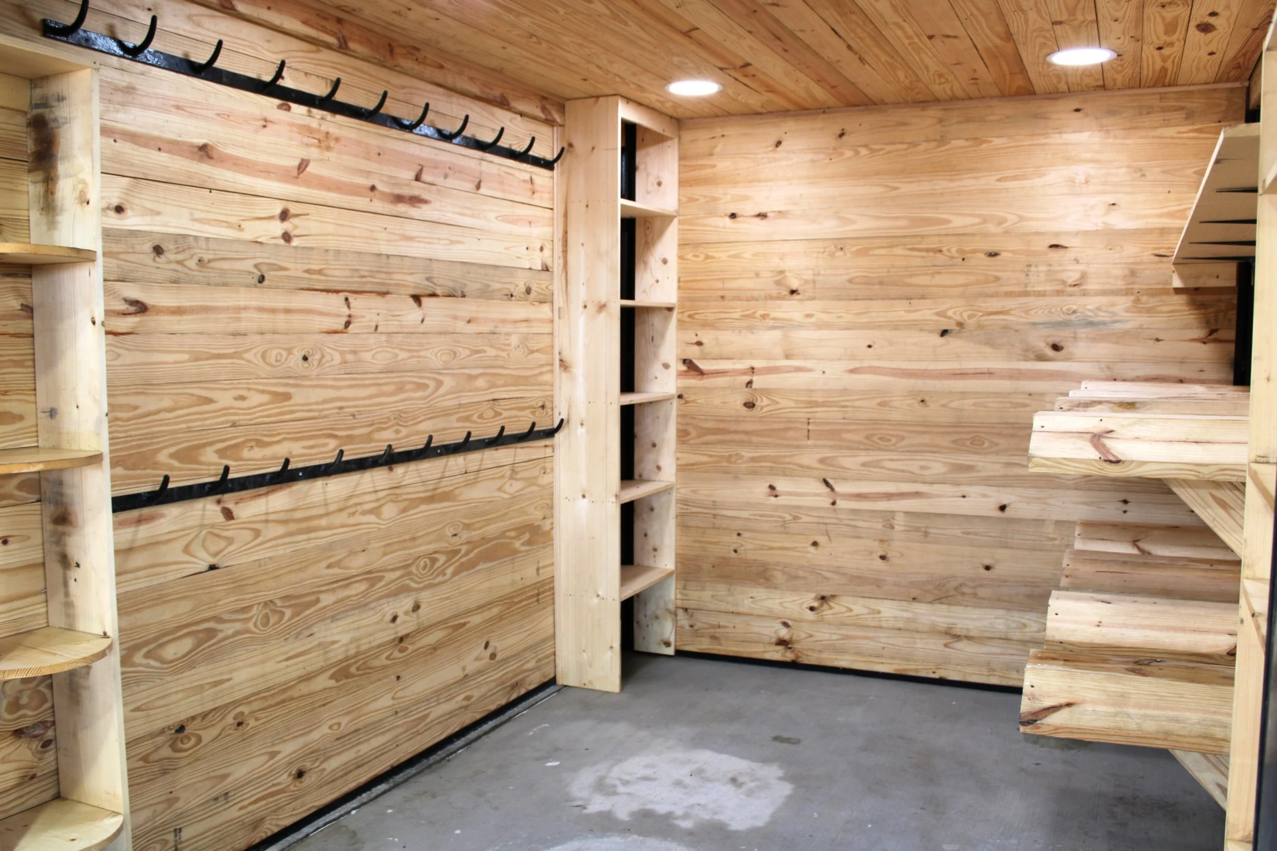 Custom pine board tack room with saddle racks, shelving, bridle hooks, roll up door in Bellville, TX