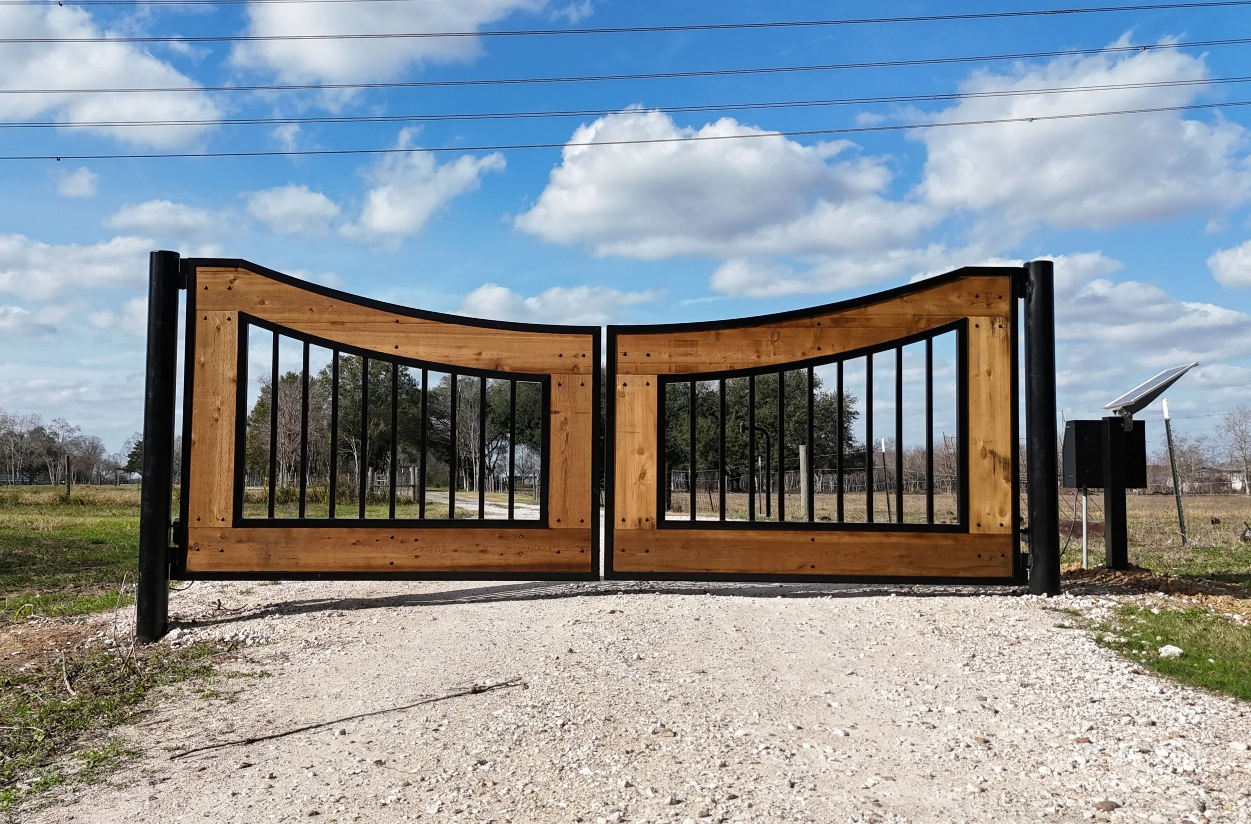 Custom built wood and black metal entrance gate in Fort Bend County, Texas.