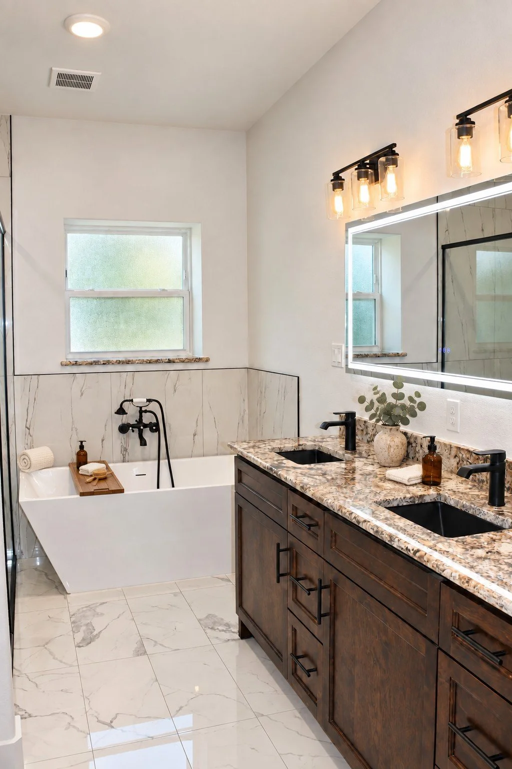 Custom primary bathroom featuring a double stain-grade wood vanity, granite countertops, black fixtures, illuminated mirror, and freestanding soaking tub.