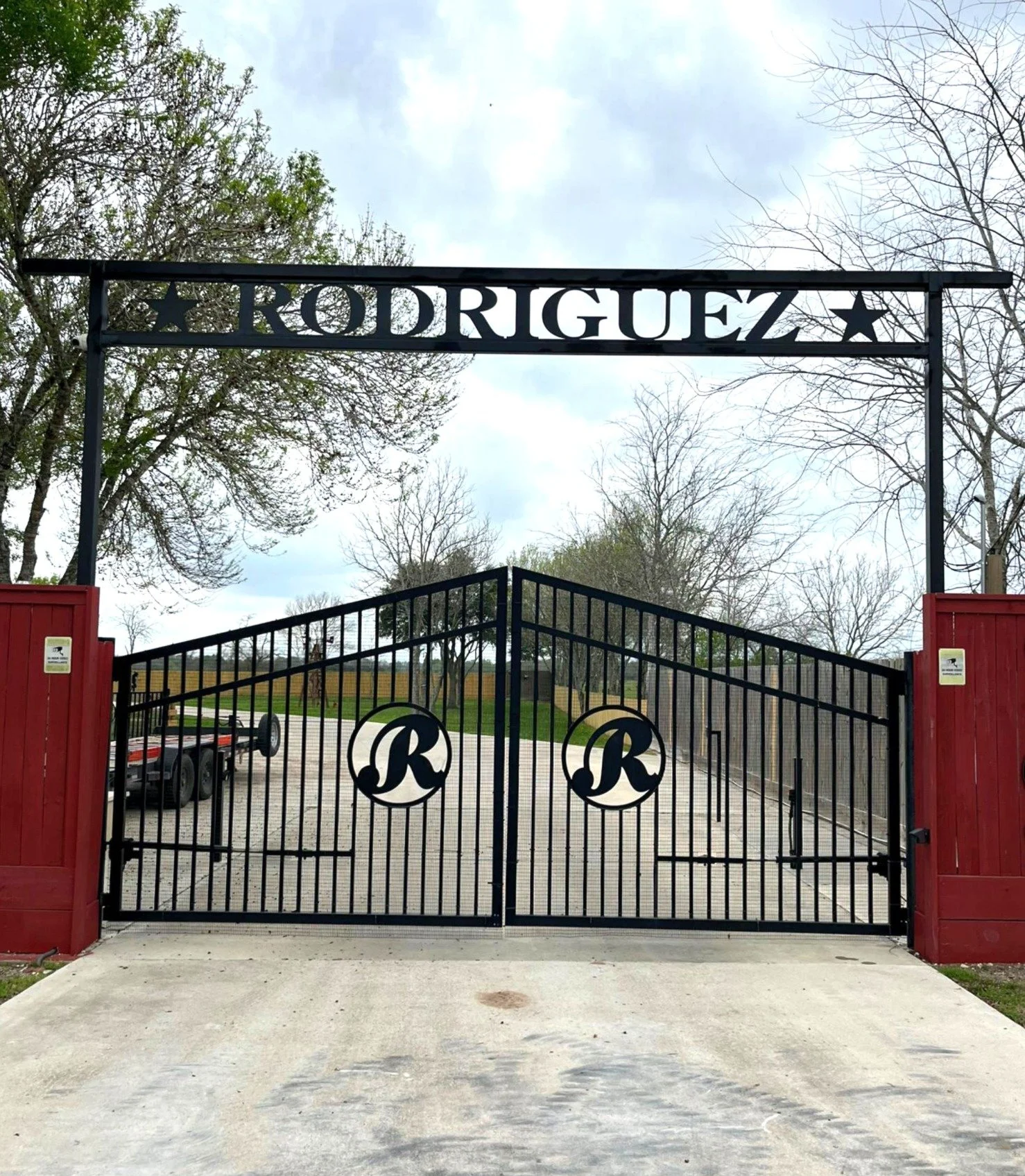 Custom black metal ranch entrance fate with name cutout and masonry pillars built in Fort Bend County, Texas.