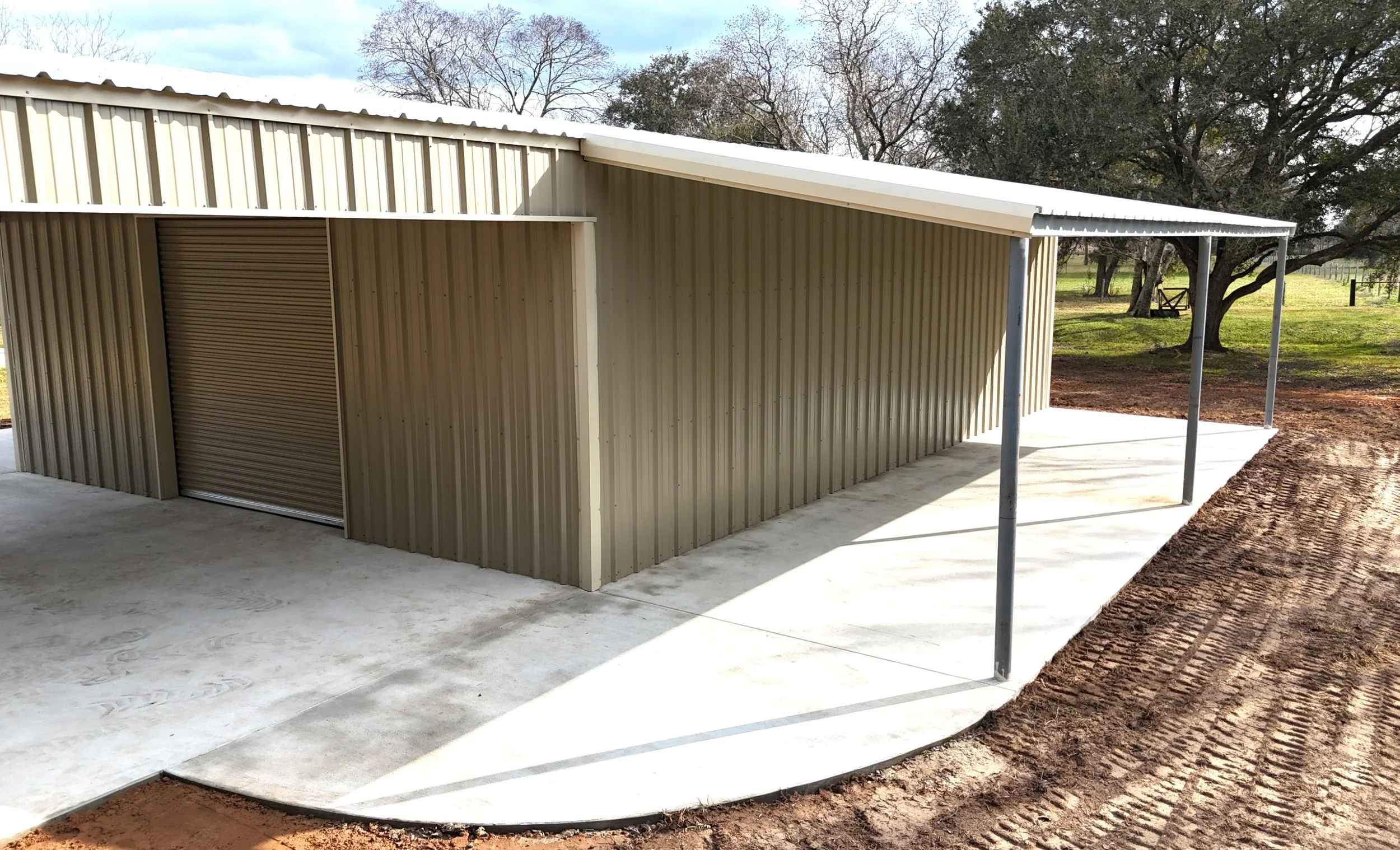 Front corner view of custom metal shop with full-length awning and reinforced concrete foundation in Brazoria County, Texas.