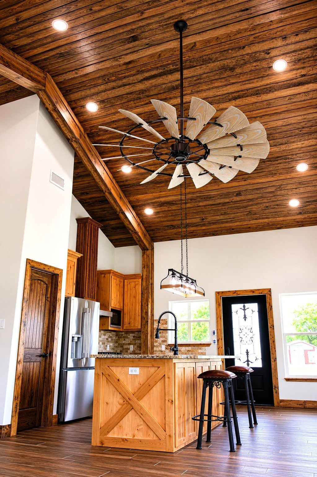 Warm rustic kitchen with vaulted wood ceilings, exposed beams, and oversized custom island in custom Lessie, TX barndominium