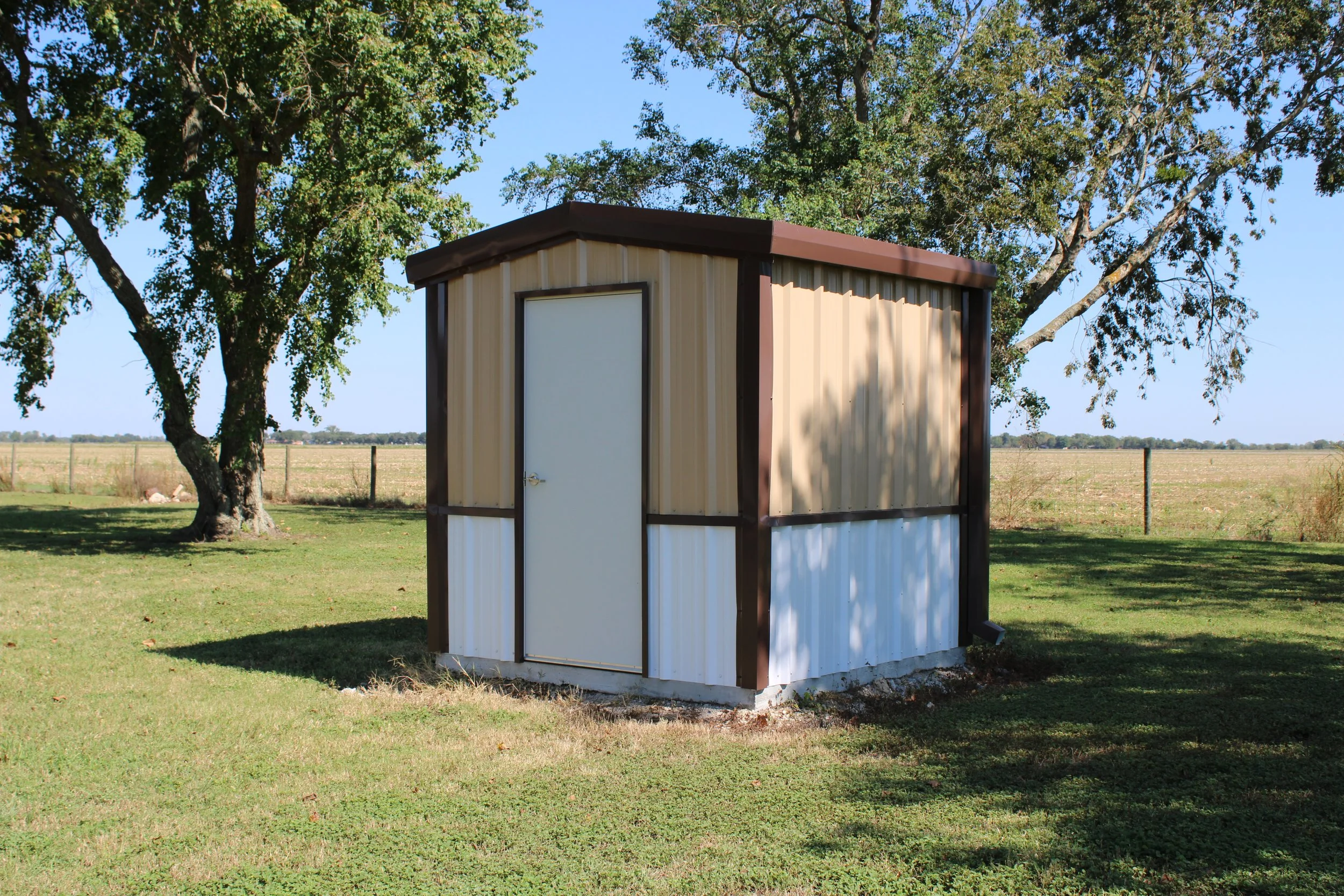 Matching metal well house with two-tone siding and white wainscot, built in Fort Bend County, Texas.