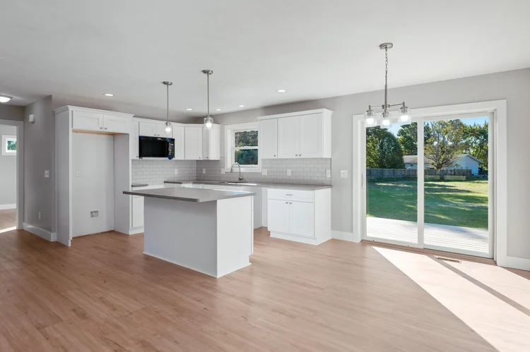 Kitchen with island, white cabinets and sliding door