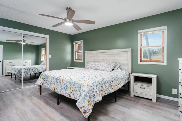 Primary bedroom with green walls and mirrored closet
