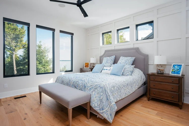 Primary bedroom with paneled wall and large windows