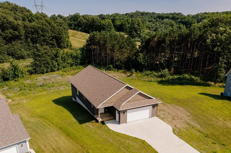 Aerial view of the home and lot beside woods