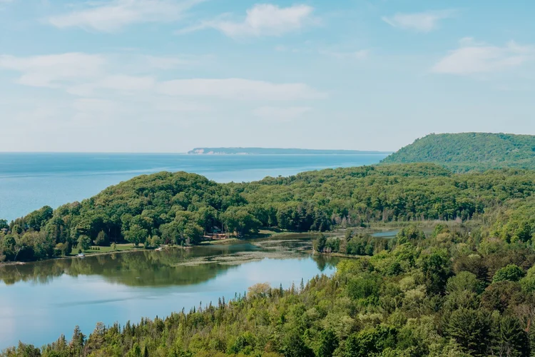 Aerial of an inland lake, wooded bluffs and Lake Michigan