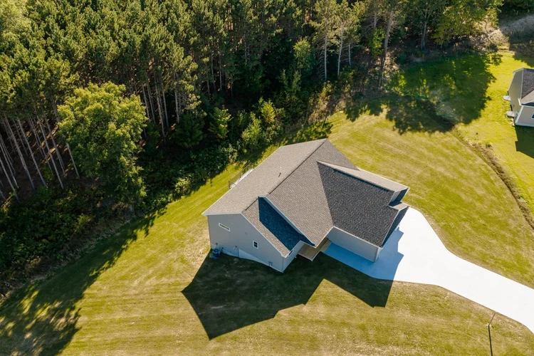 Aerial view of the home and lot beside woods