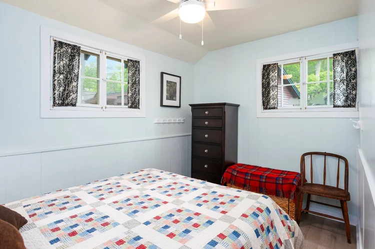 Bedroom with quilt covered bed and dresser