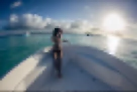 Persona en la cubierta de un yate en el mar durante el atardecer con cielo nublado.