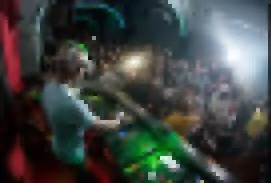 Persona jugando en máquina de arcade en un ambiente oscuro con muchas luces brillantes.