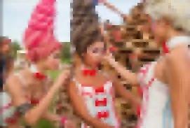 Tres niños en una fiesta, comiendo algo, vestidas con ropa de verano y decoraciones coloridas.