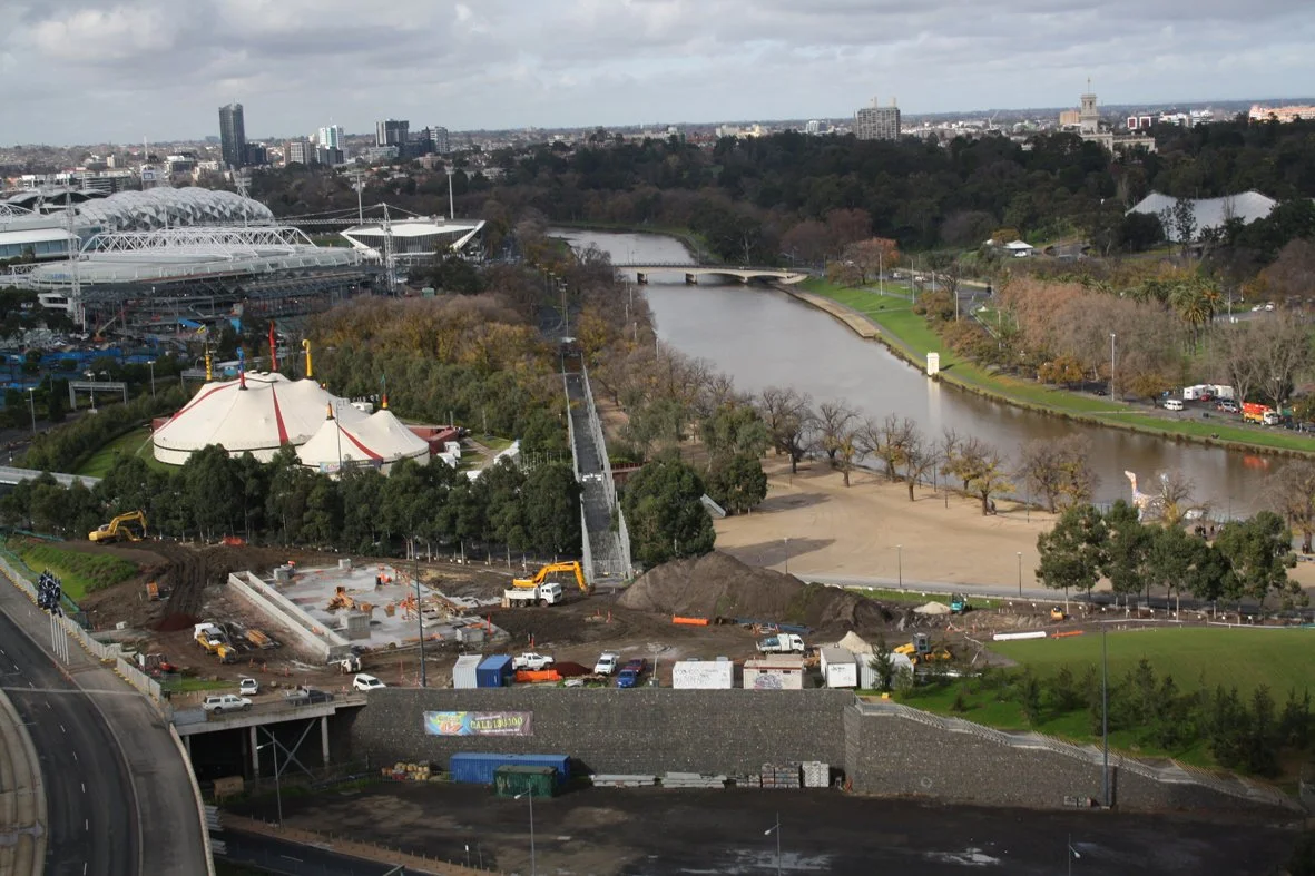 Aerial view of a city with a river, construction site, amusement park, and sports stadium.