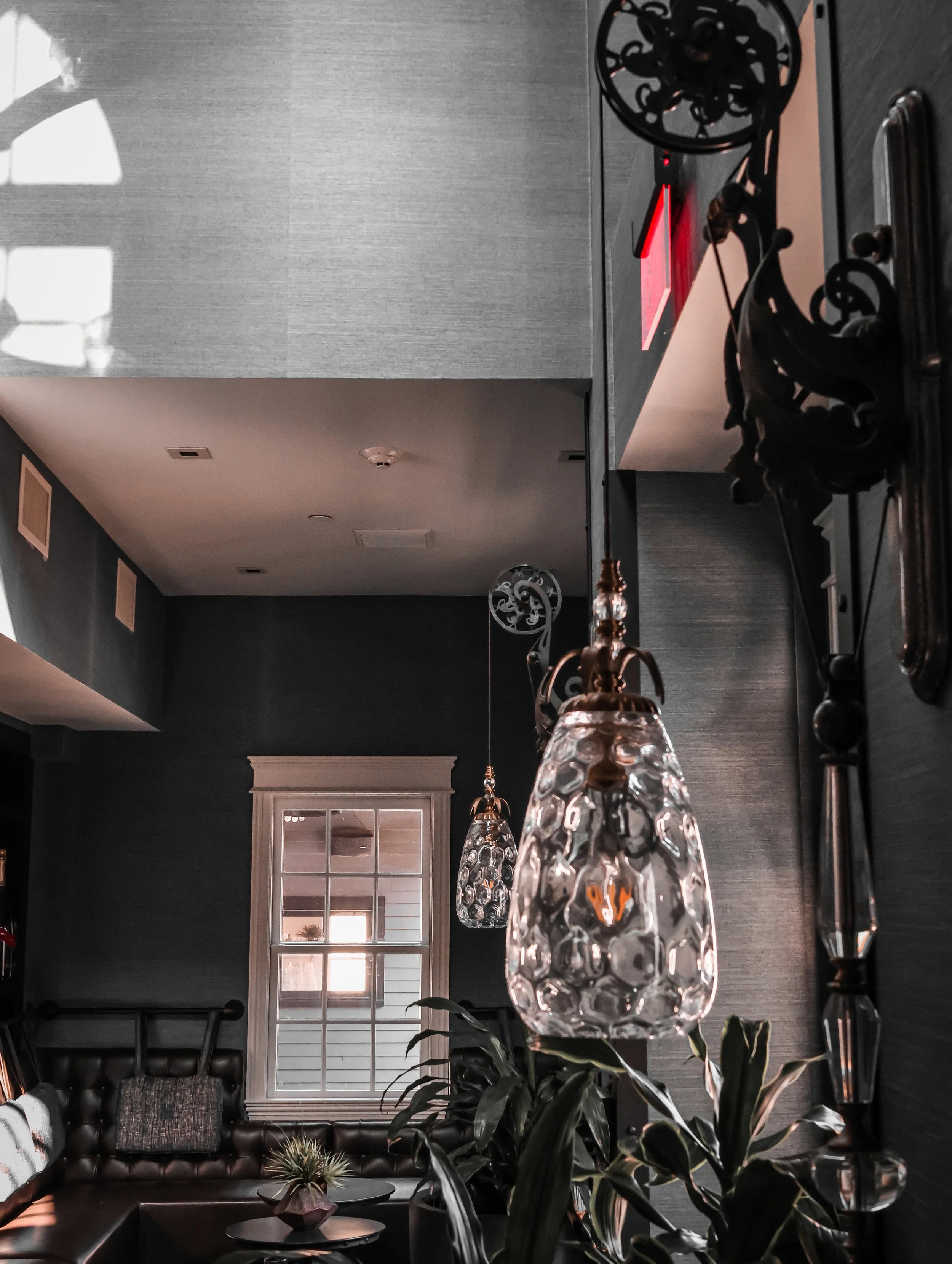 Interior of a living room with dark walls, a window, and hanging glass pendant lights.