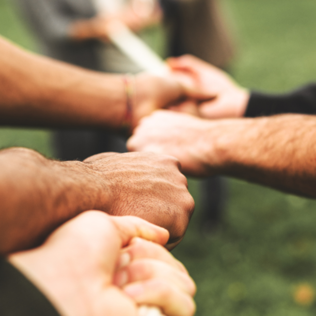 Close-up of diverse hands joined together in a line, symbolizing unity and teamwork.