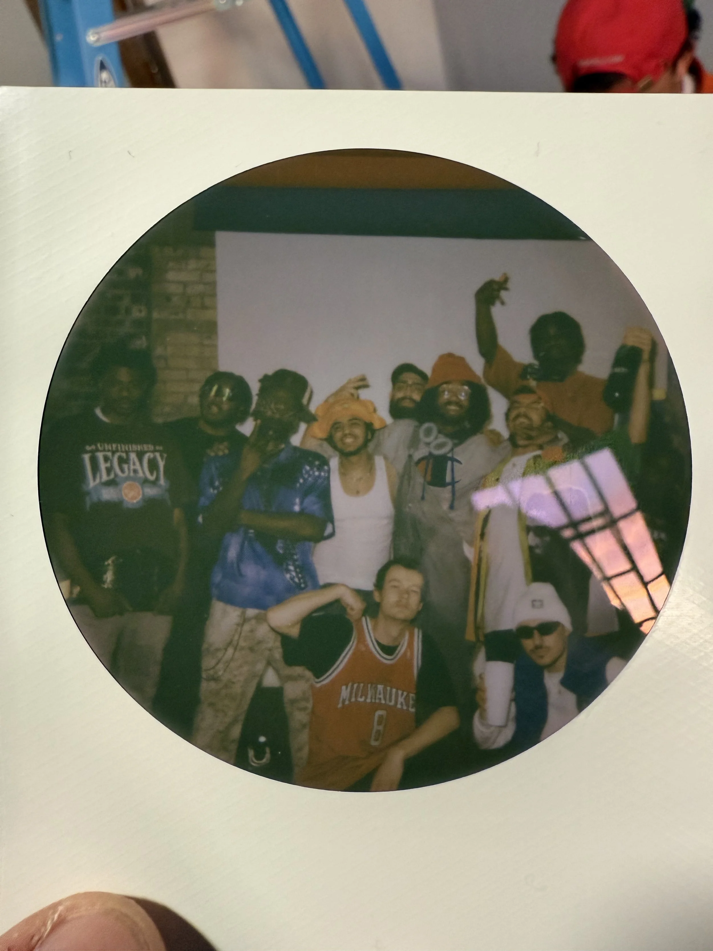A group of people standing together, some wearing hats and sports jerseys, posing for a photo in an indoor setting.