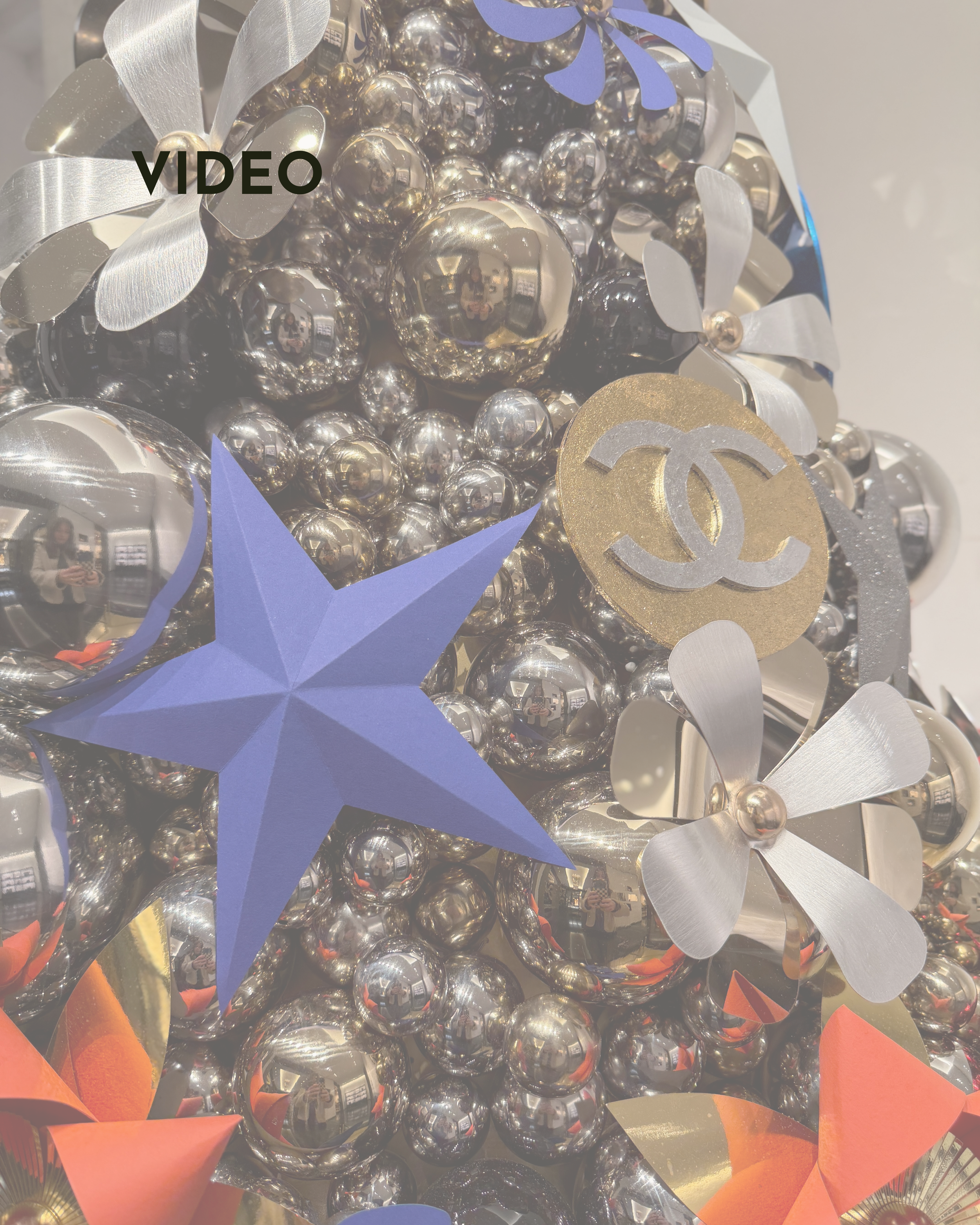 A silver christmas tree made up of silver balls with a Chanel logo decoration