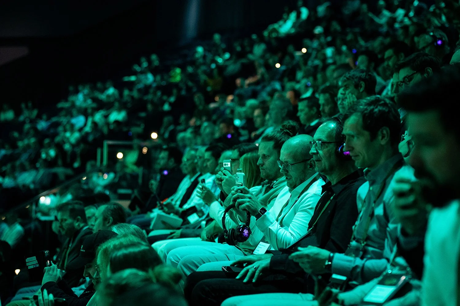 Audience members sitting in dark theater, some taking photos or videos, dressed in business attire, attending the Data Hero Summit.