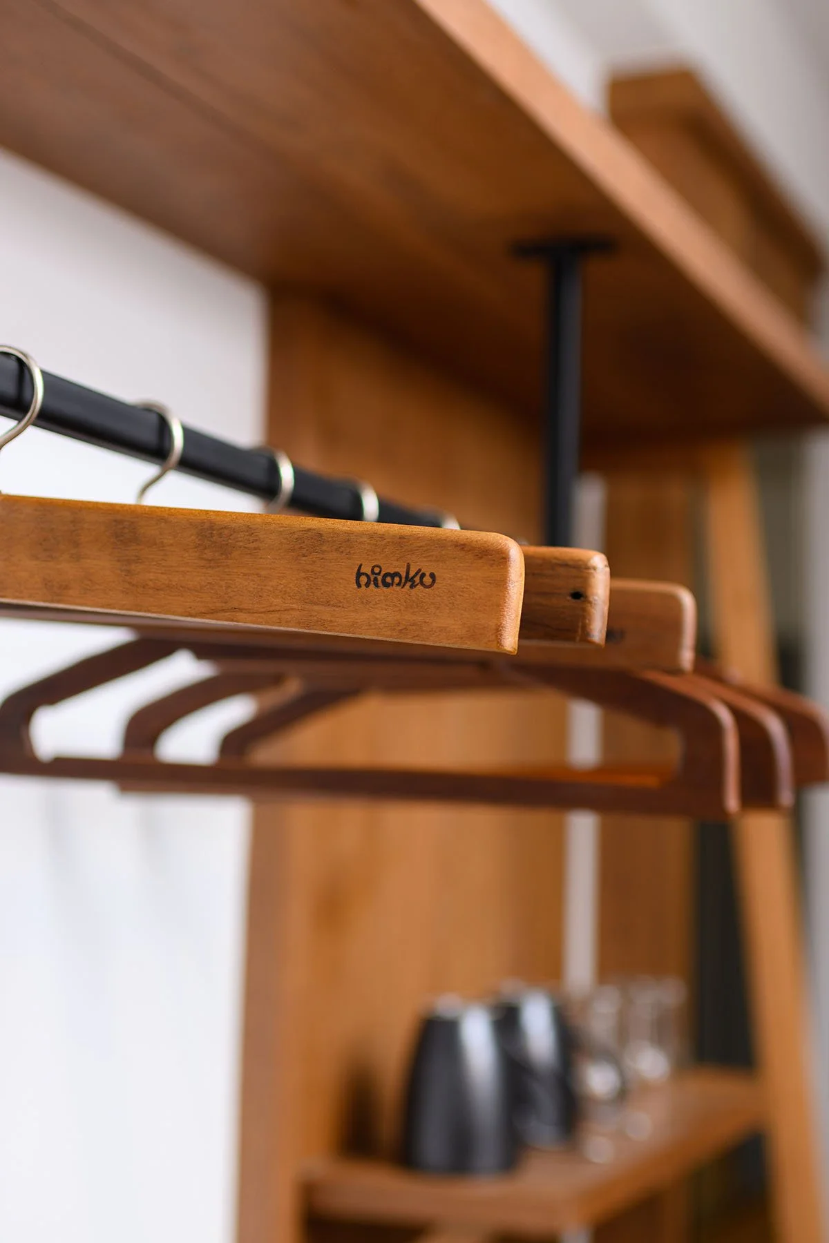 Wooden closet with empty hangers and a close-up of a wooden hanger labeled 'himaku'