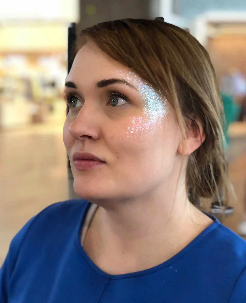 Vaalean turkoosi, kevyt glitteri naisen ohimolla ja poskipäällä. Fresh looking glittermakeup.