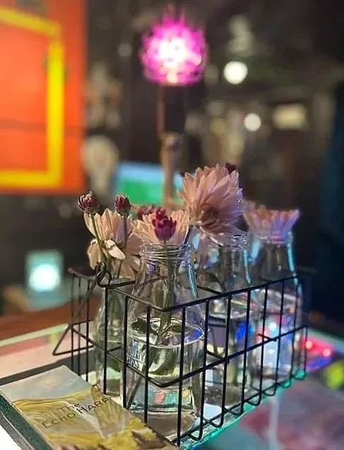 Pienissä lasipulloissa on kukkasia tumman tunnelmallisessa luokkahuoneessa Theatrum Olgassa.